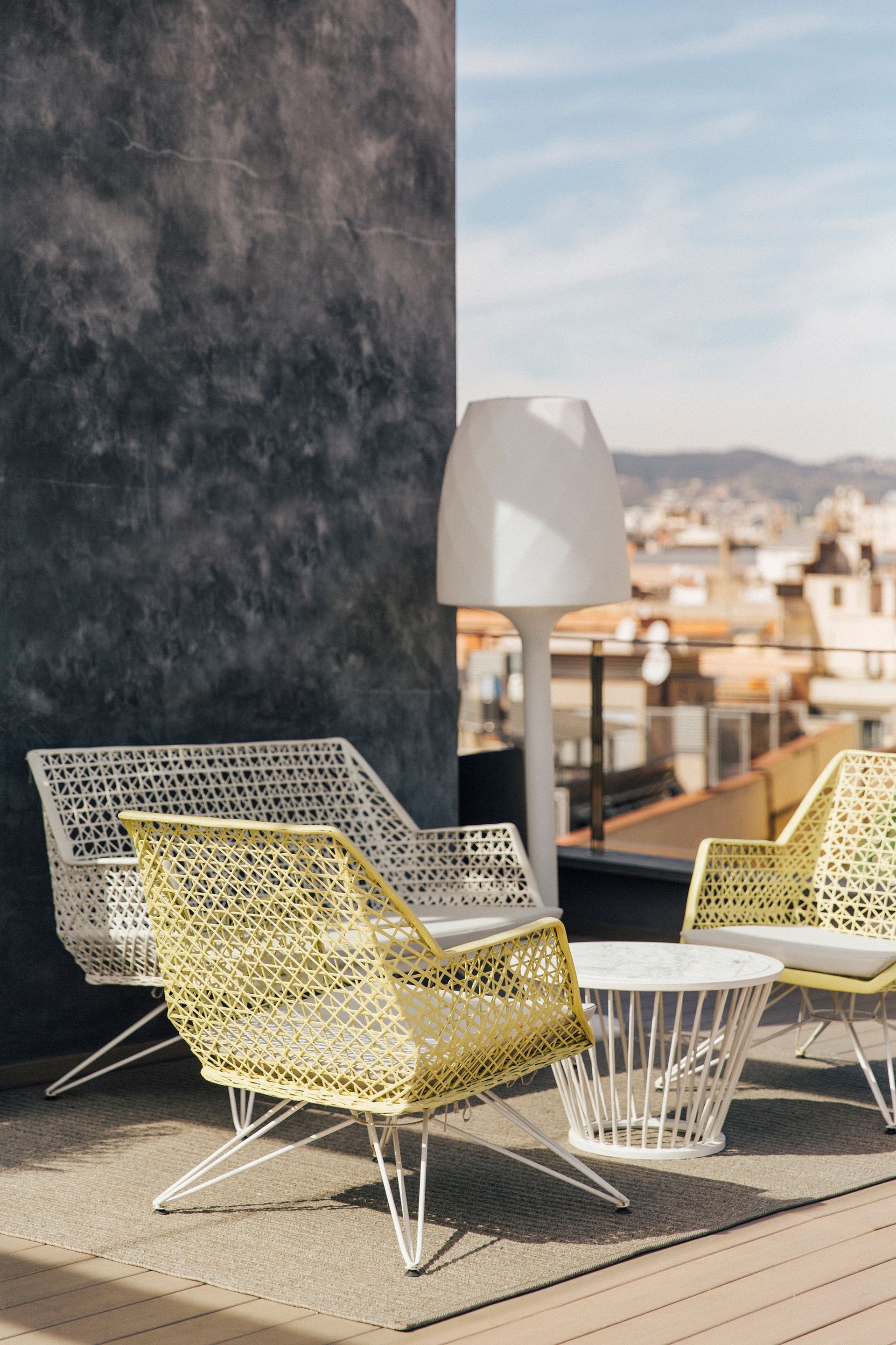 A patio with yellow chairs, a table, and a lamp at Hotel Bagués in Barcelona, Spain.