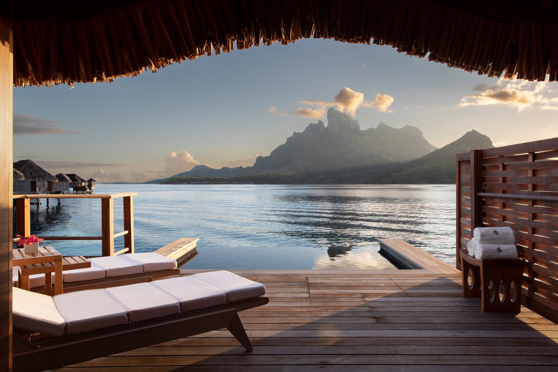 A wooden deck with an infinity pool overlooking Bora Bora at Four Seasons overwater bungalow resort. 