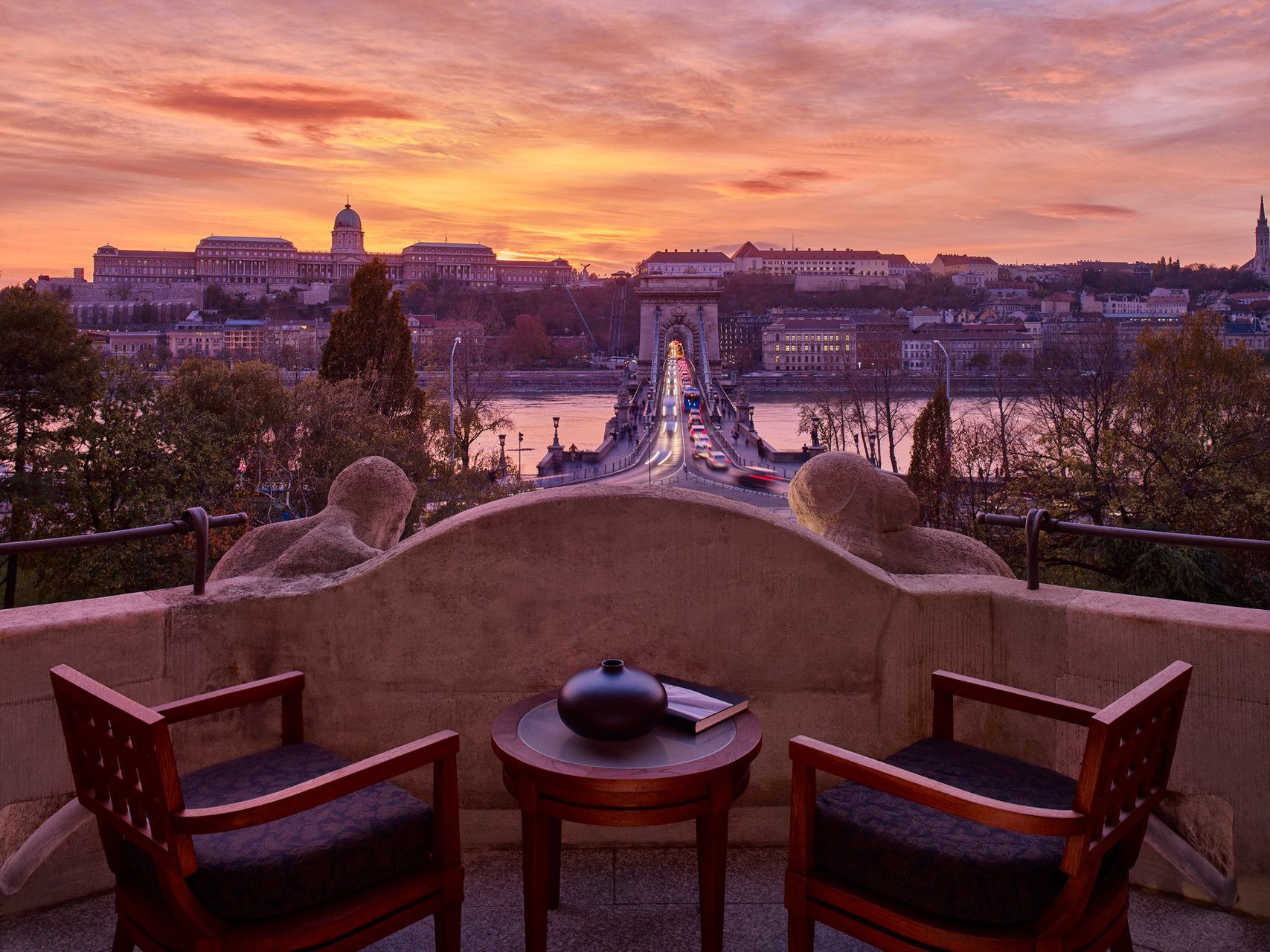 A balcony with two chairs and a table with a view of Budapest, Hungary sunset at Four Seasons Hotel.