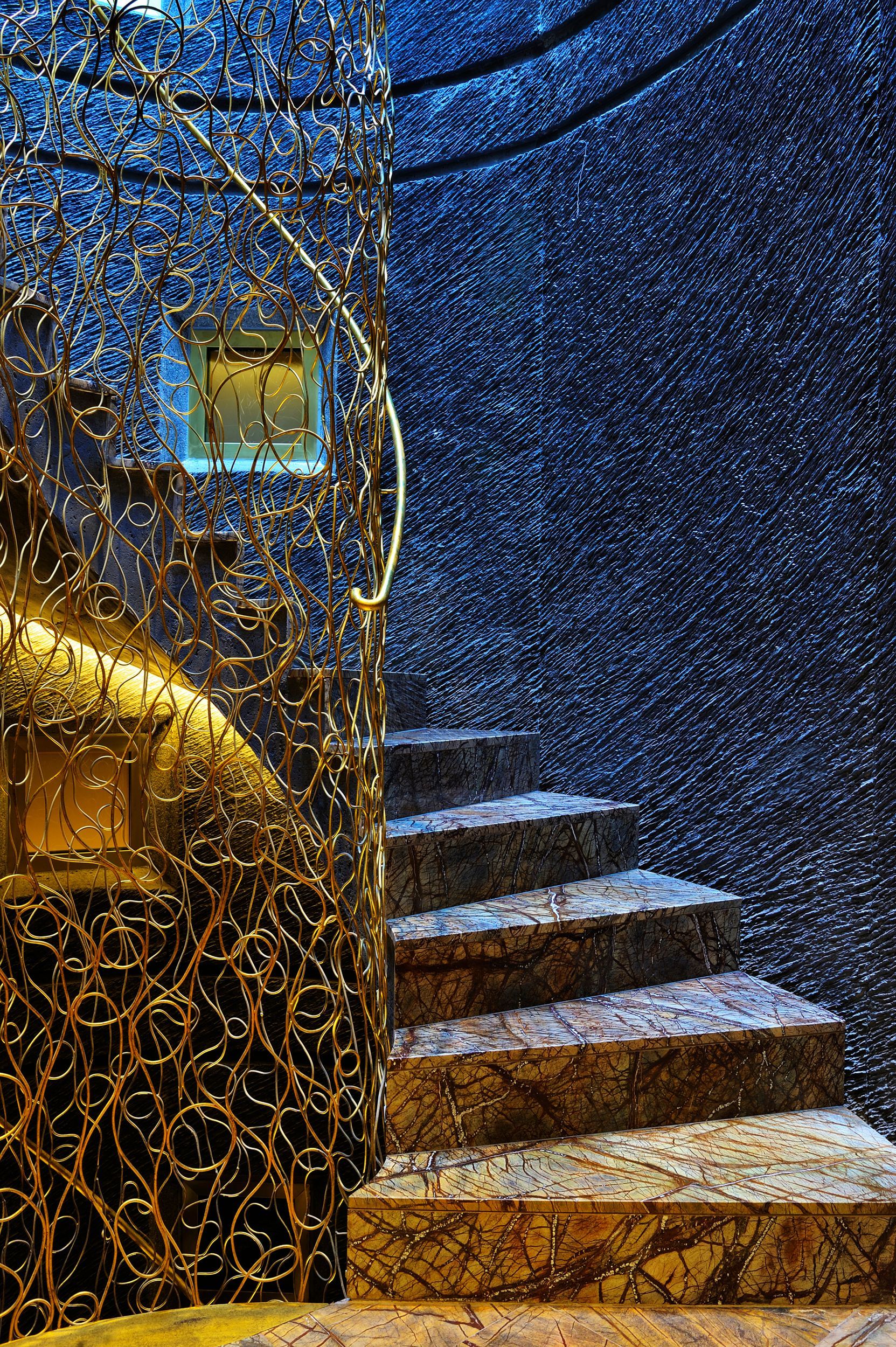 A staircase leading up to a dark room with a blue wall at Hotel Bagués in Barcelona, Spain.