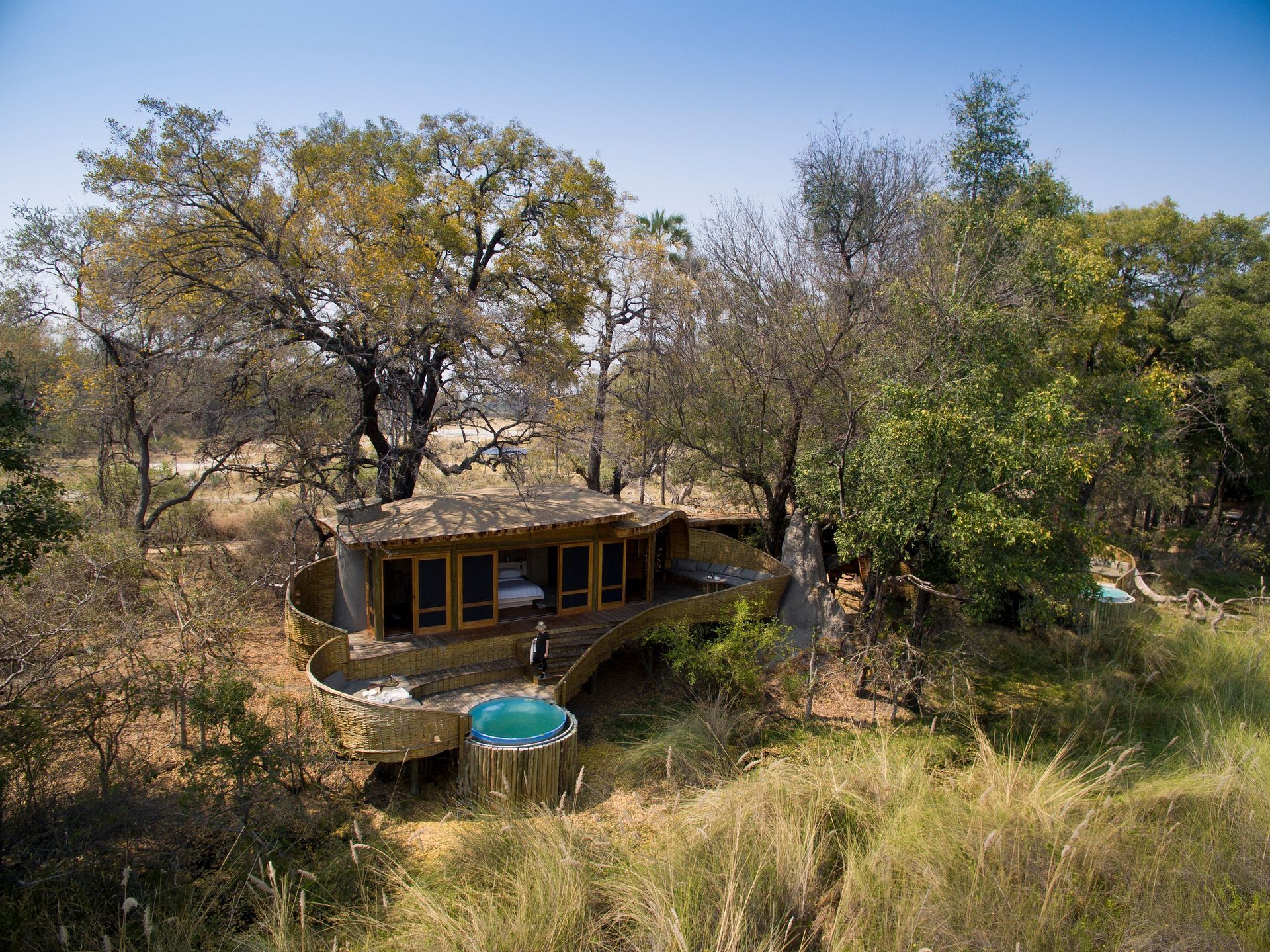 An aerial view of a lodge in the middle of a forest surrounded by trees in Africa.