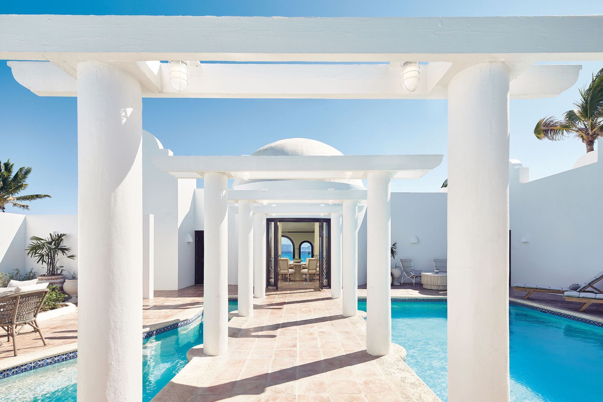 A white house with a large swimming pool in front of it in Anguilla, Caribbean at Belmond hotel. 