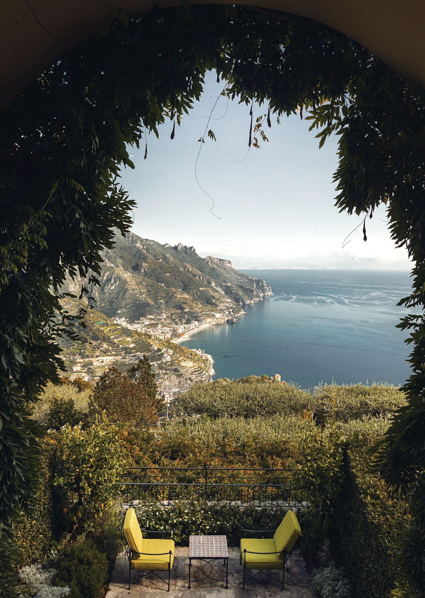 A view of the Amalfi coast from a balcony with yellow chairs at Belmond hotel. 
