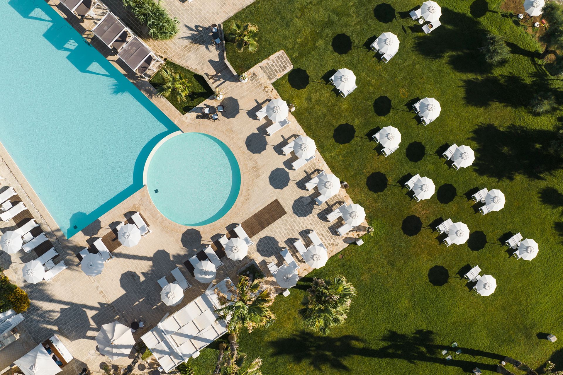 An aerial view of a swimming pool surrounded by umbrellas and chairs at Canne Bianche Lifestyle Hotel in Puglia, Italy