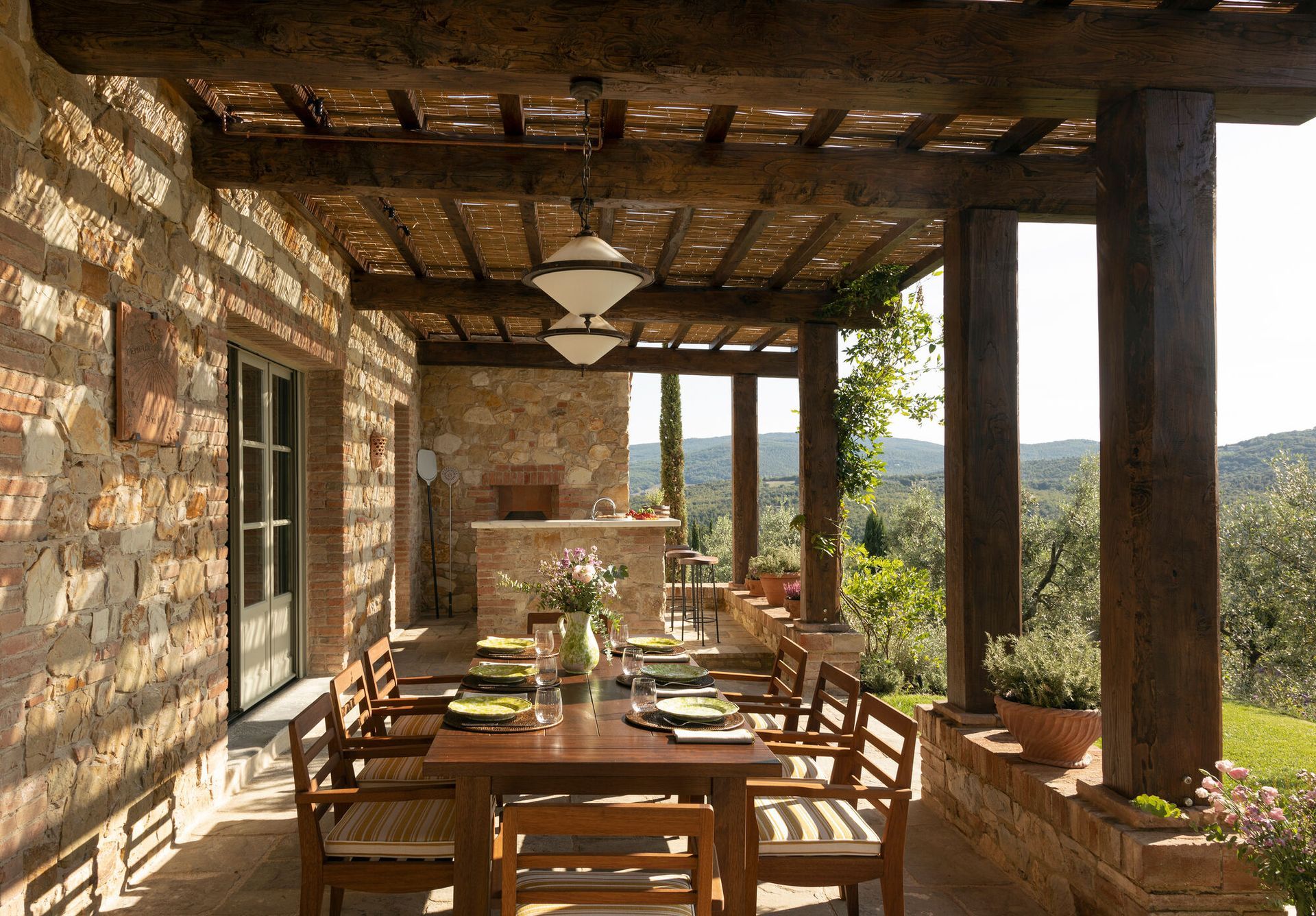 A patio with a table and chairs under a wooden roof in Tuscany Italy at Belmond Hotel. 