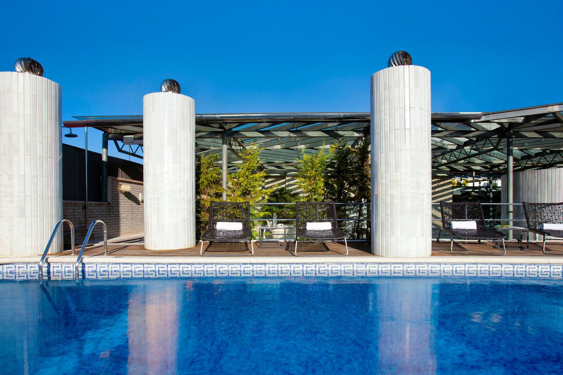 A large swimming pool surrounded by columns and chairs at Claris Hotel & Spa in Barcelona, Spain.