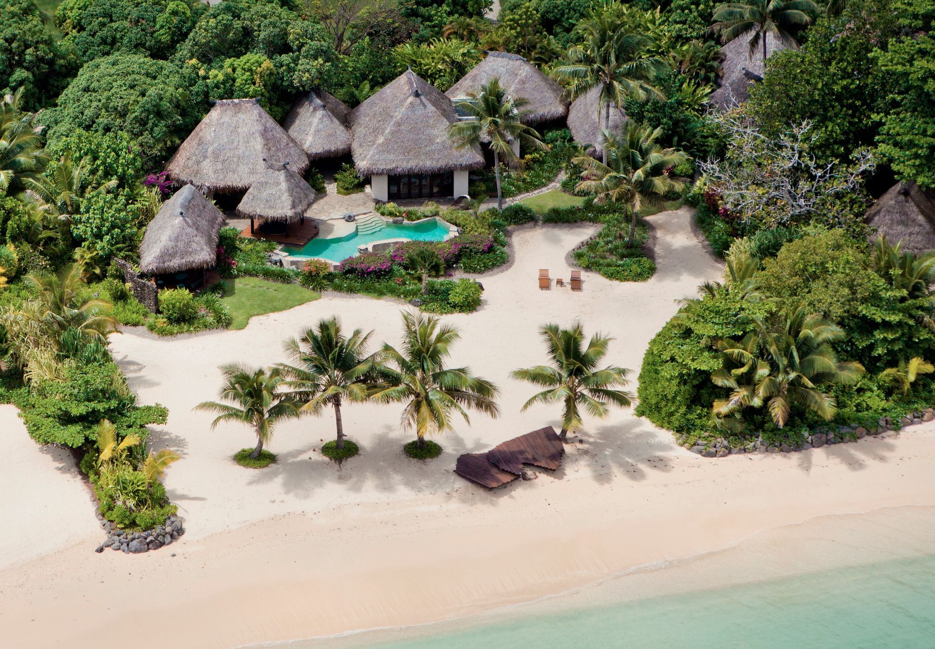 An aerial view of a tropical island with palm trees and villas in Fiji.