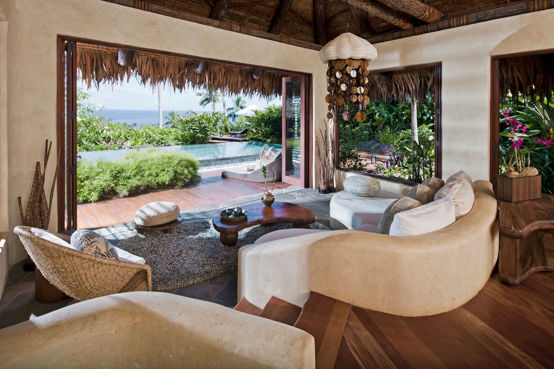 A living room with a couch, chairs and a table with a view of the ocean at villa in Fiji.