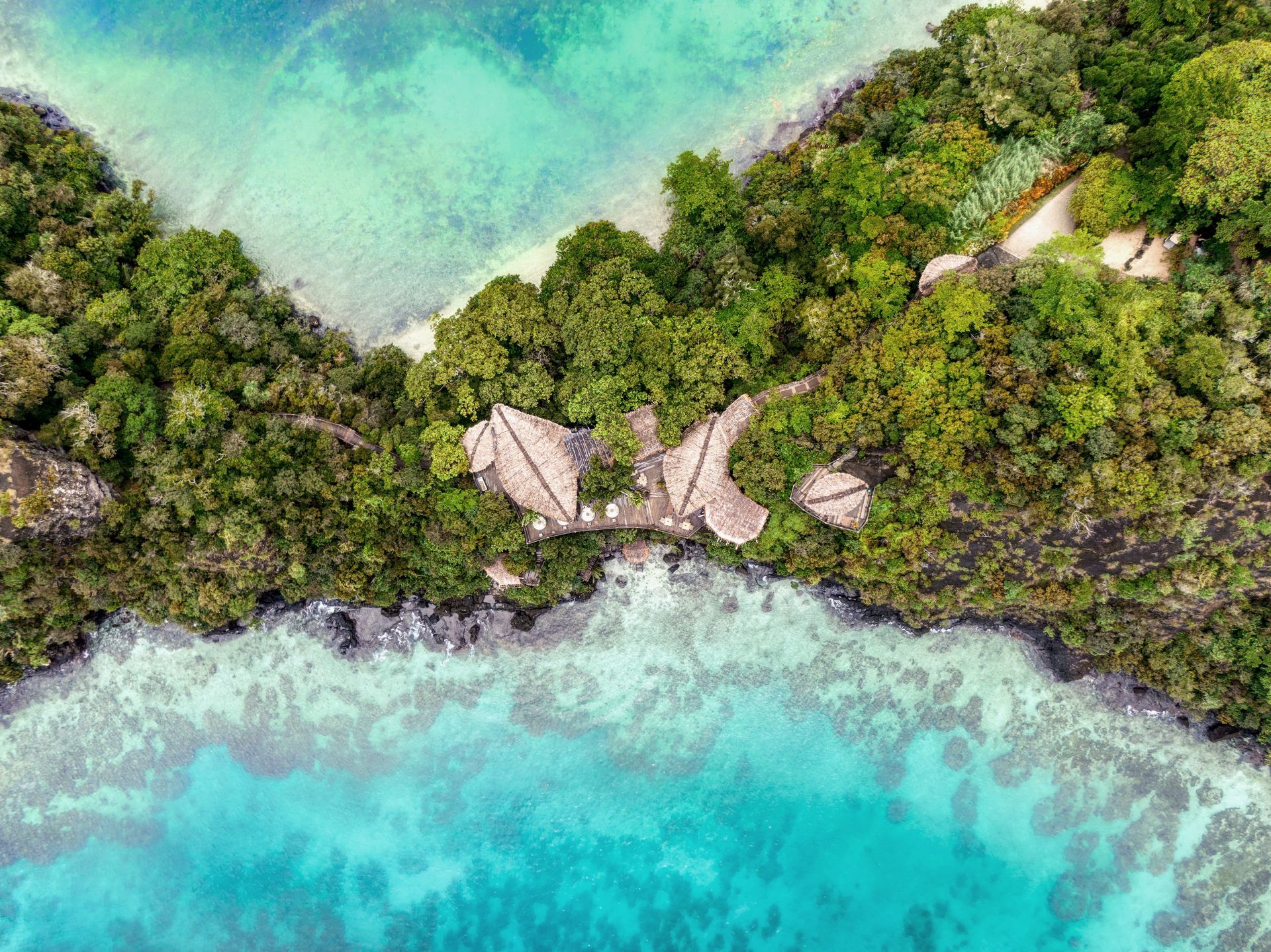 An aerial view of a tropical island with villas surrounded by water and trees in Fiji.