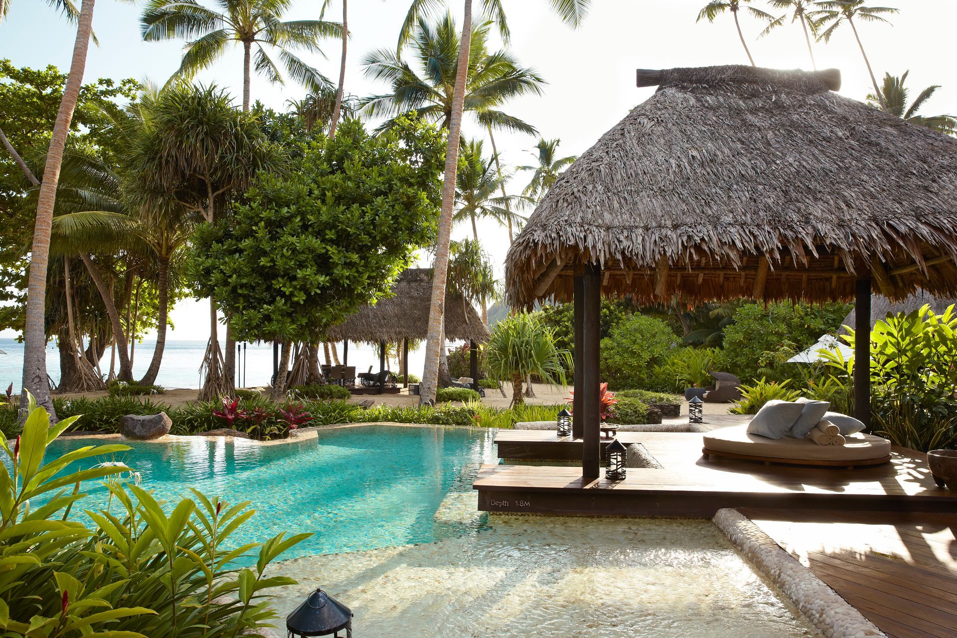 A swimming pool with a thatched villa in the background in Fiji.