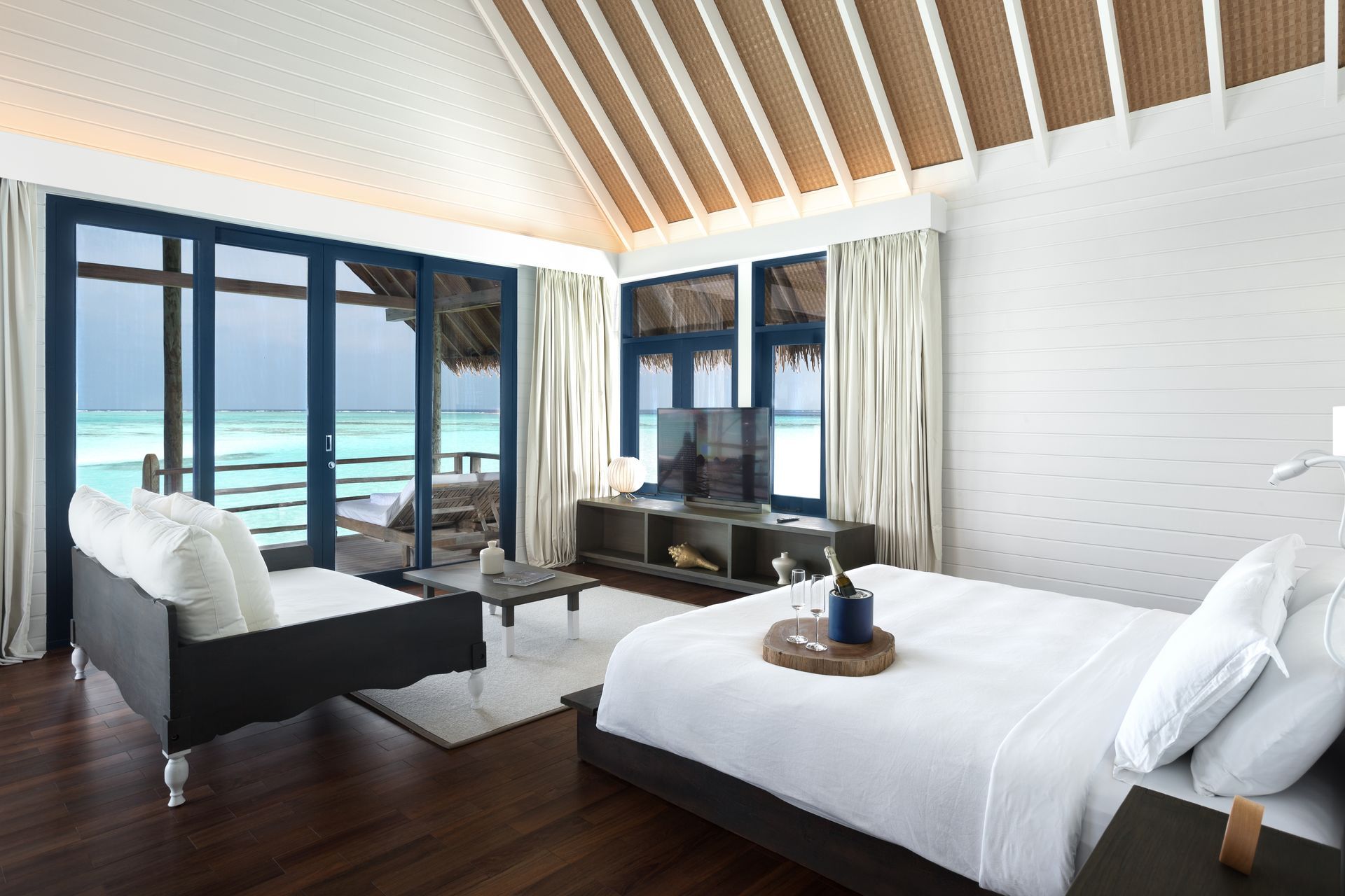 There is a large bed in the middle of an overwater bungalow at como resort in the Maldives. 