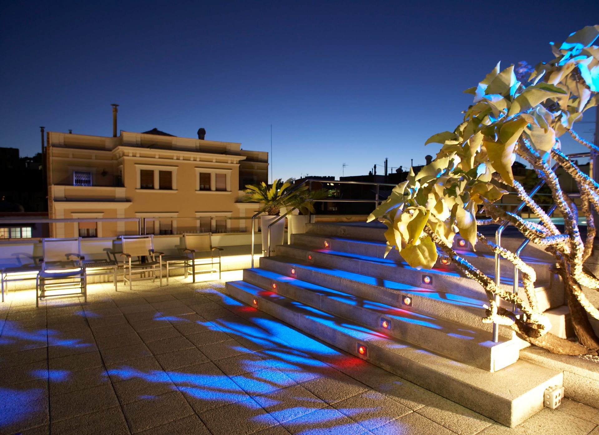 A tree is lit up with blue lights in front of a building at Claris Hotel & Spa in Barcelona, Spain.