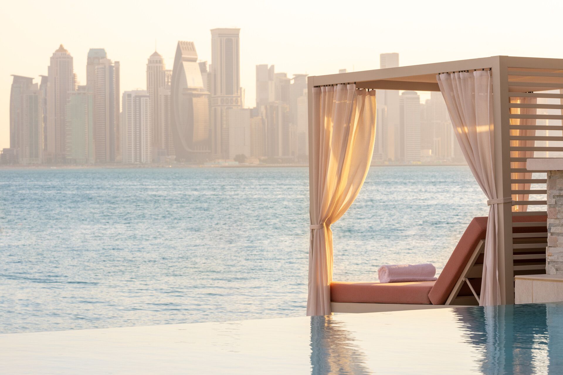 A canopy over a swimming pool with the Doha, Qatar skyline in the background at Four Seasons Hotel.