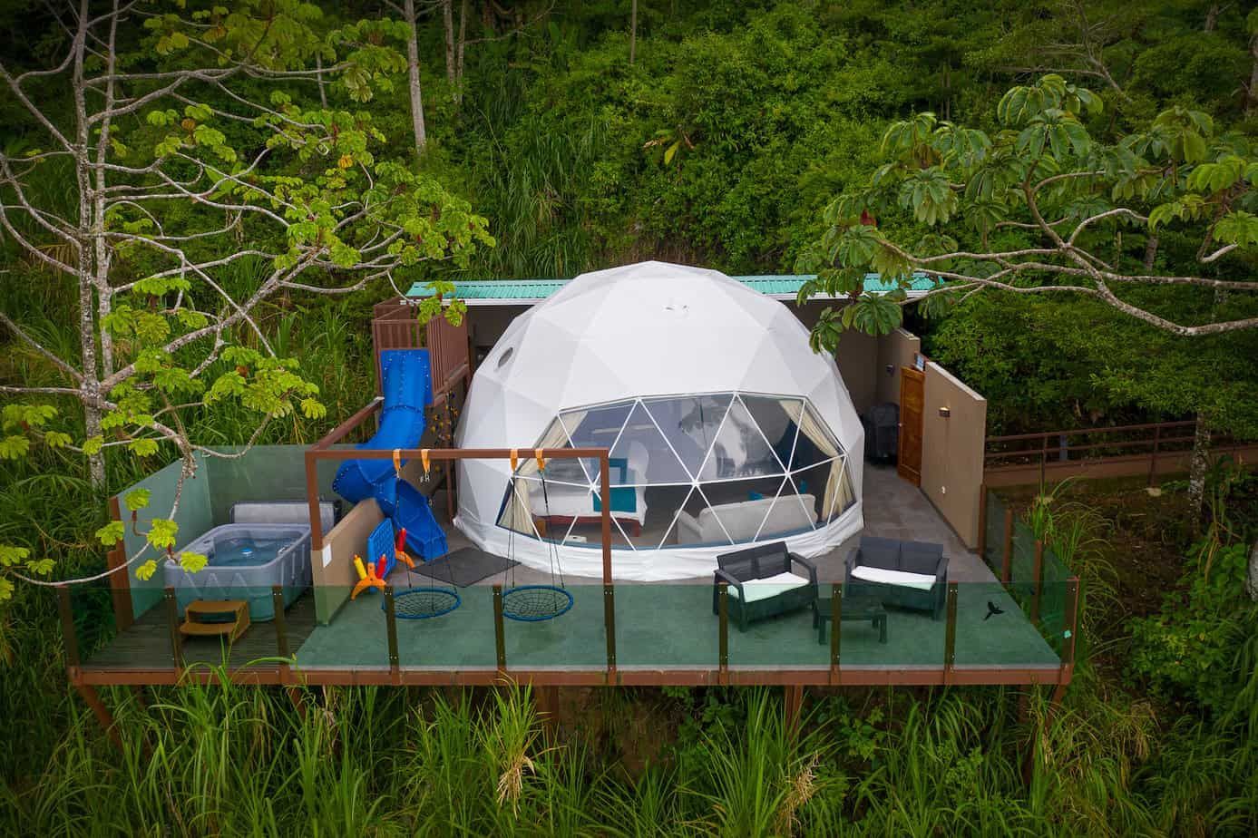 An aerial view of a dome tent in the middle of a forest in costa rica. 