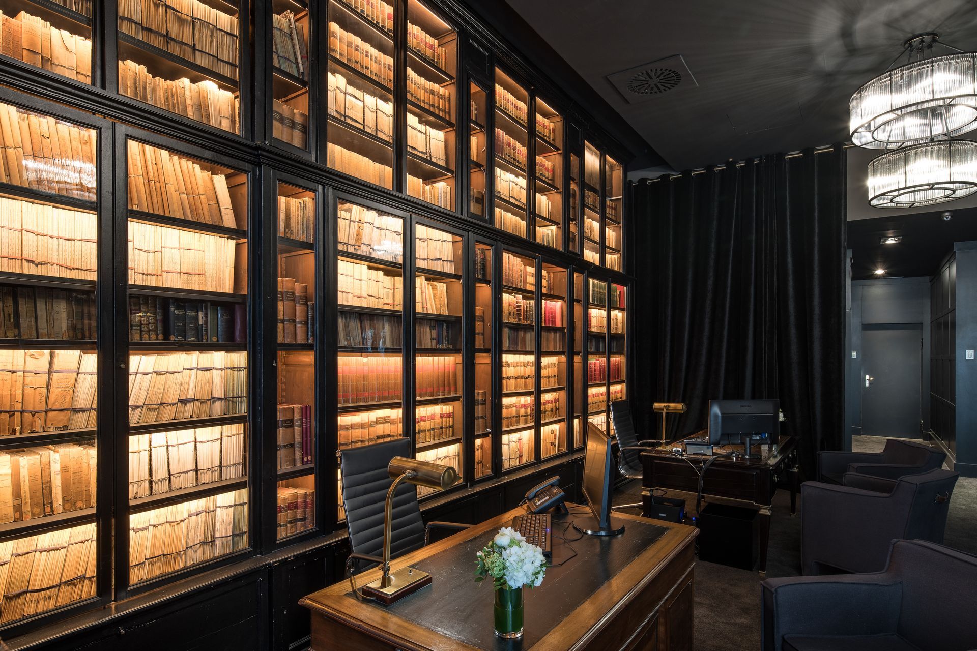 A room with a desk and chairs in front of a wall of bookshelves at Grand Hotel Central in Barcelona, Spain.