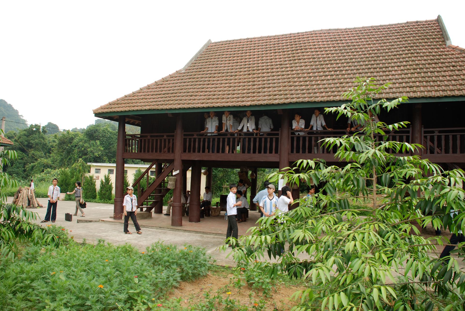 Red Vespa scooter parked on asphalt near a lake and trees.