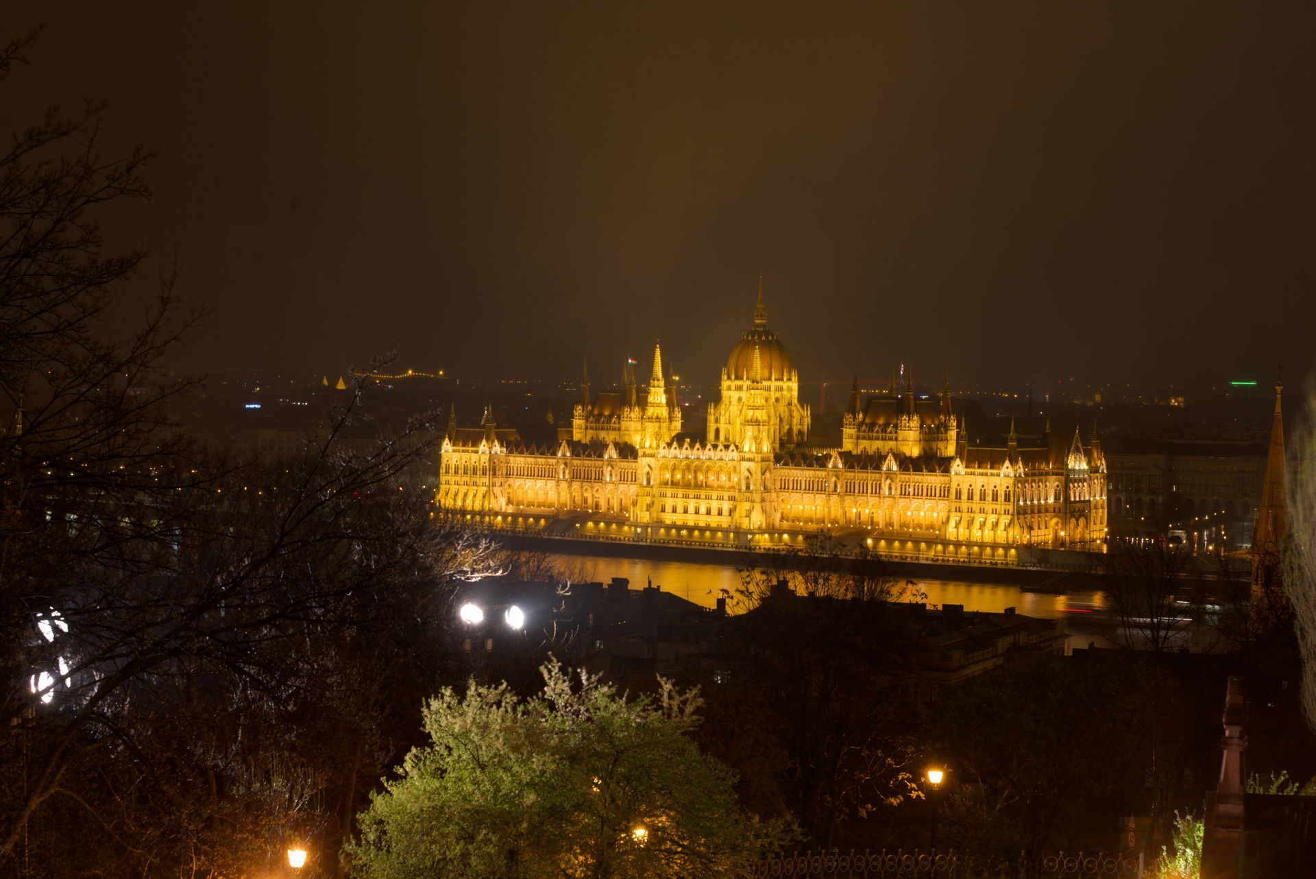 Illuminated Hungarian Parliament Building at night, reflecting in the water.