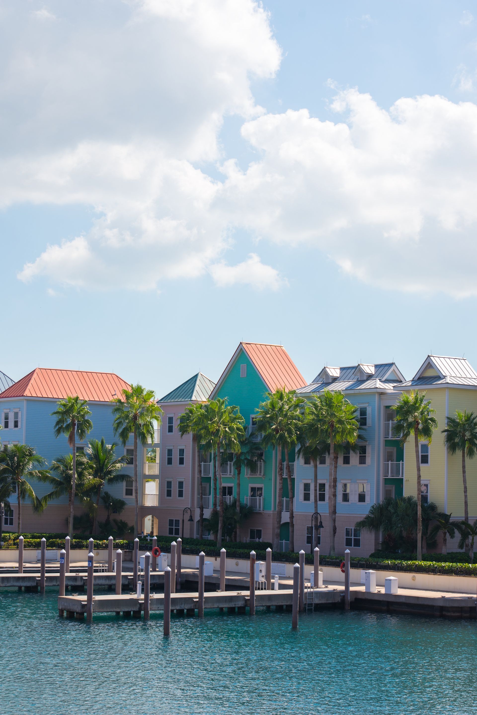 Colorful buildings line a waterfront dock, palm trees, blue sky.