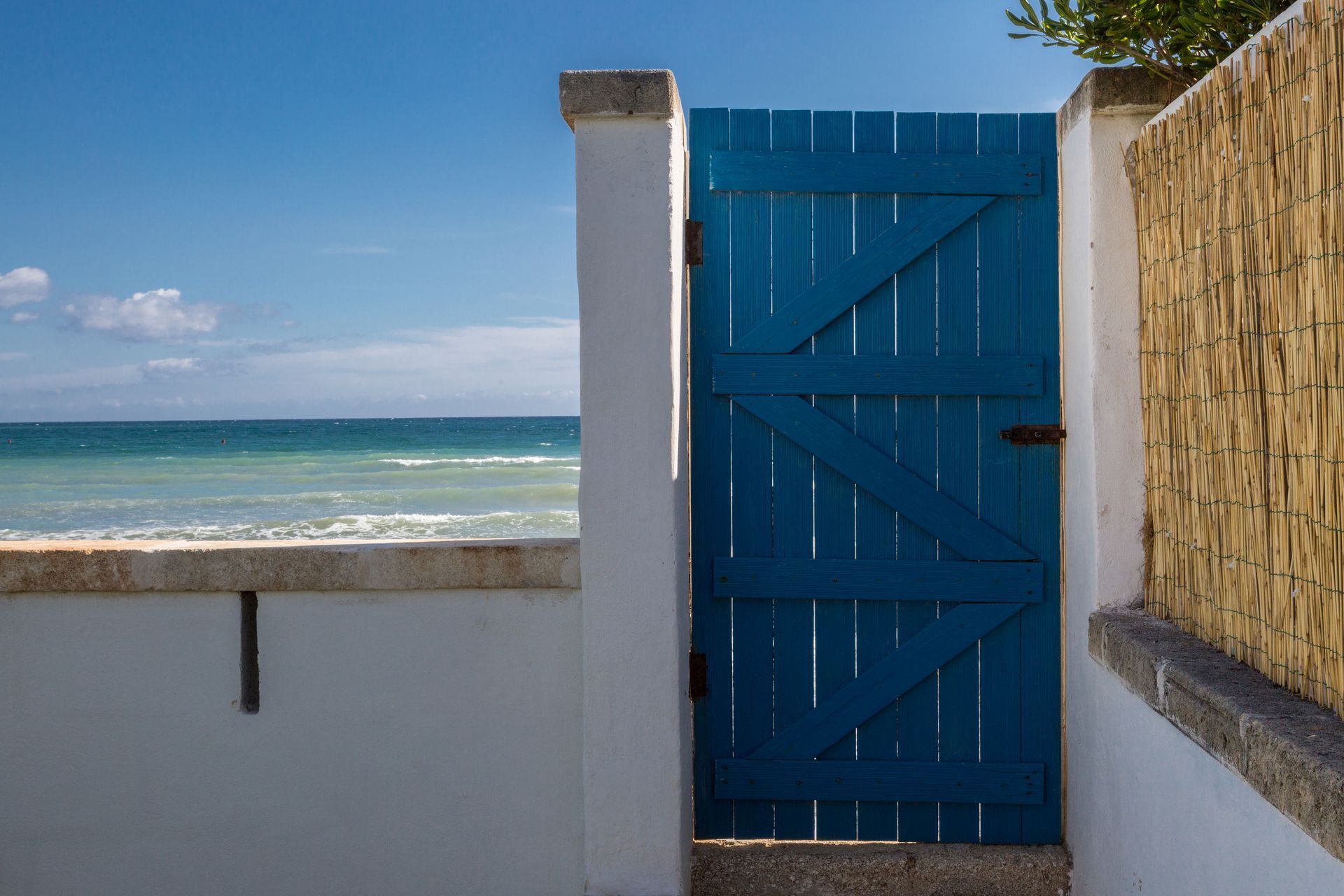 A blue wooden gate is leading to the beach at Canne Bianche Lifestyle Hotel in Puglia, Italy.