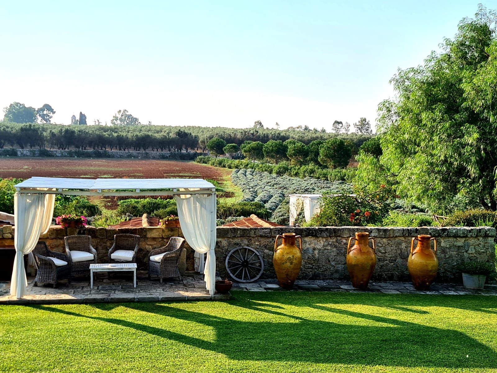 There is a gazebo in the middle of a lush green field at Naturalis Bio Resort & Spa in Puglia, Italy.