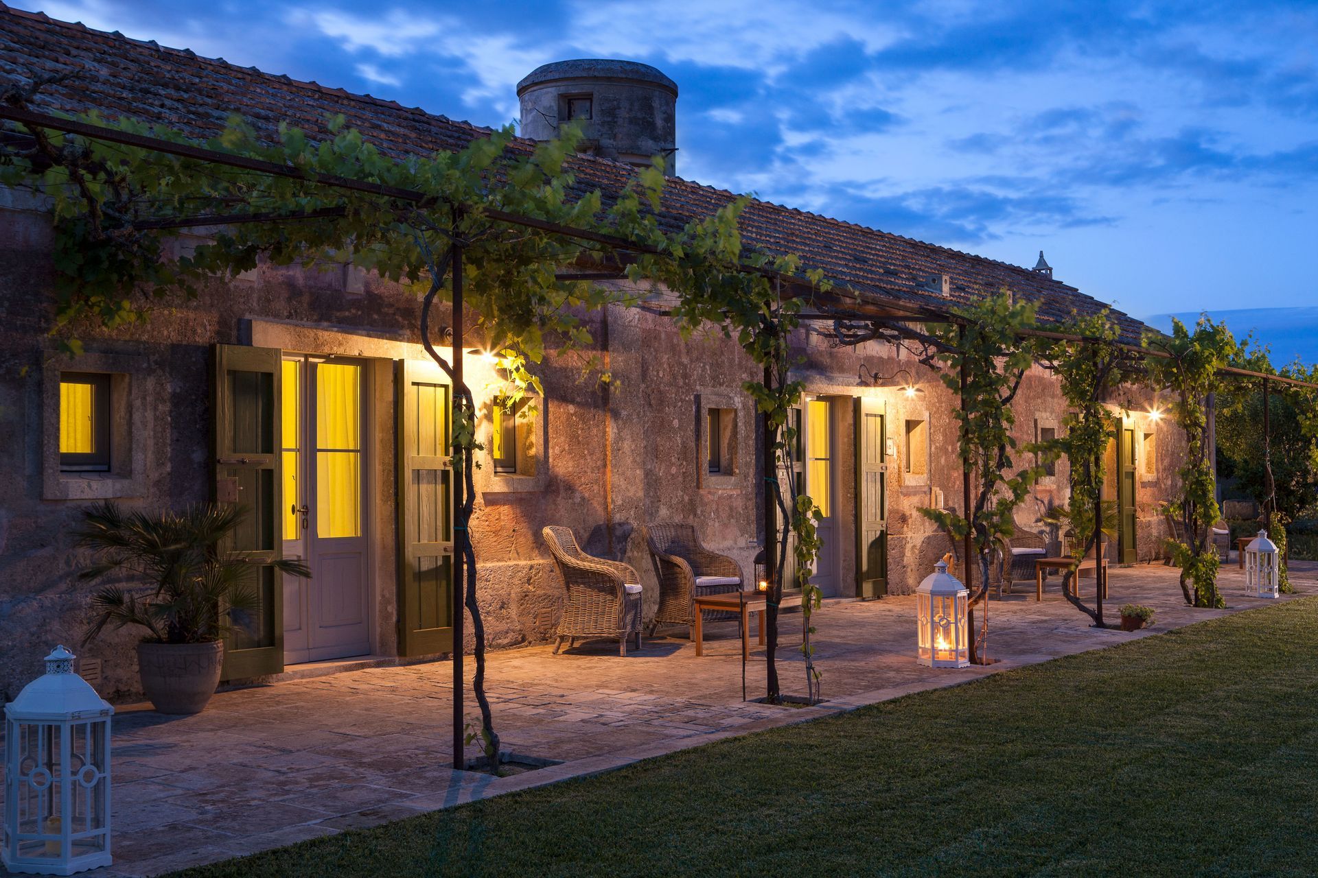 A stone house with a pergola and a patio at night at Naturalis Bio Resort & Spa in Puglia, Italy.