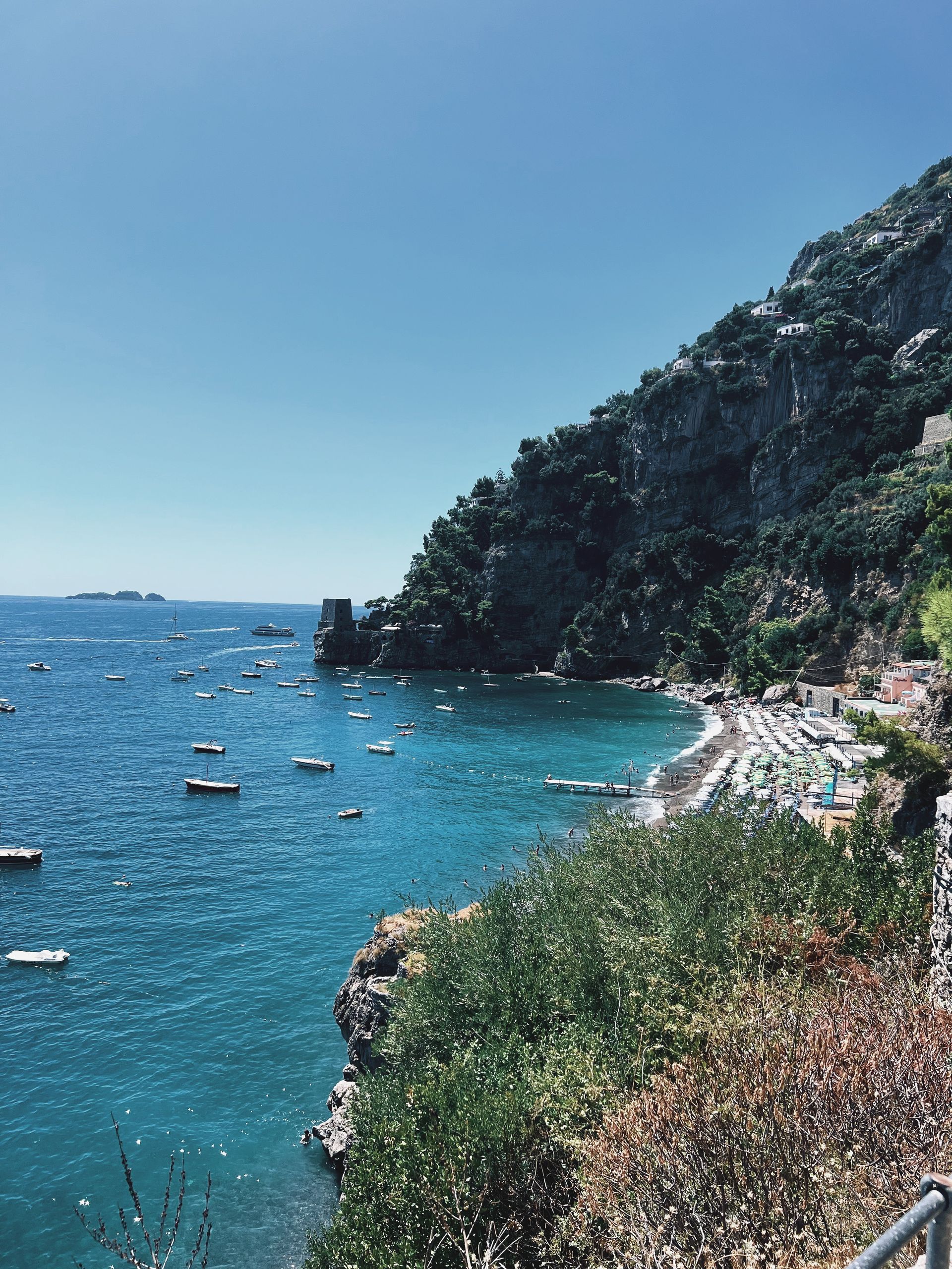 A cliff overlooking a body of water with boats on the Amalfi Coast, Italy.