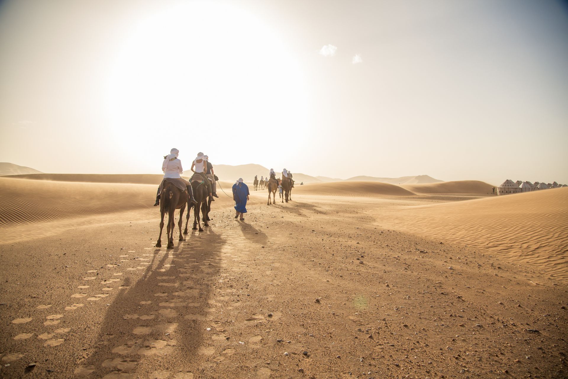 A group of people are riding camels through the desert in Morocco.