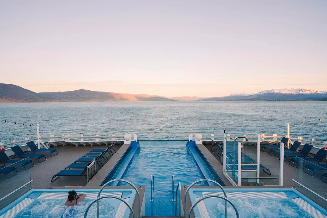 A woman is sitting in a jacuzzi on the deck of Hurtigruten Expeditions' MS Fridtjof Nansen cruise ship.