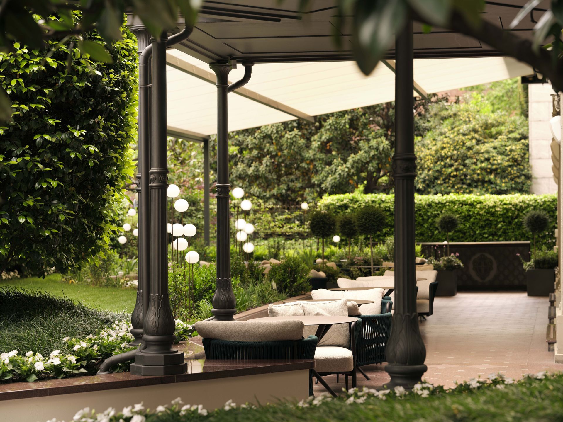 There is a gazebo in the middle of a garden surrounded by trees at the Dorchester Collection hotel in Milan.