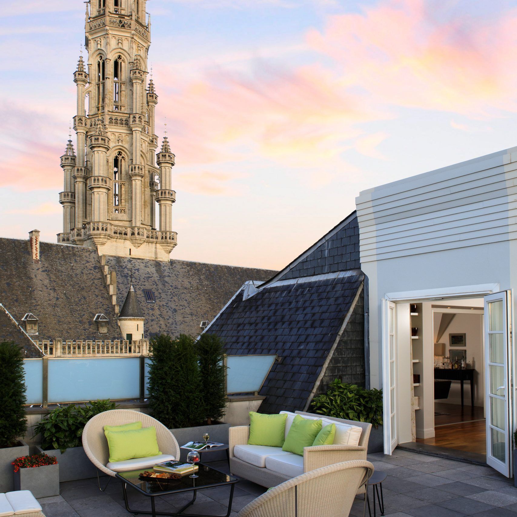 A balcony with furniture and a clock tower in the background in Brussels, Belgium at Rocco Forte Hotel.