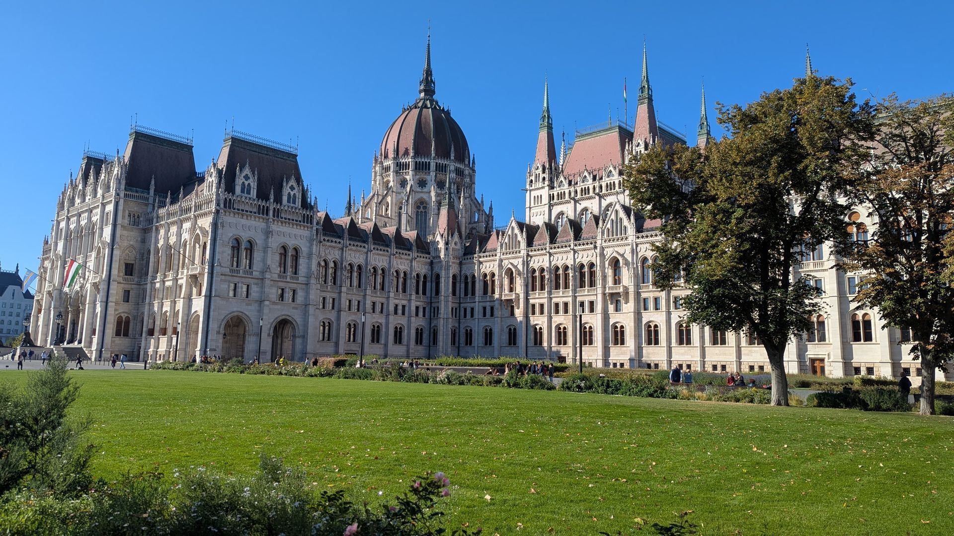 Hungarian Parliament Building on a sunny day with green lawn in the foreground.