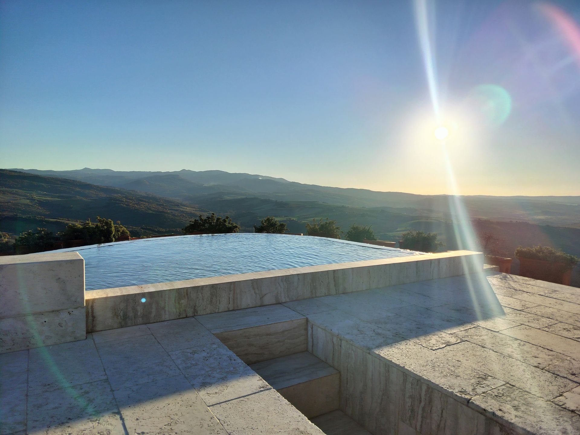Infinity pool overlooking a vast landscape under a bright sun.