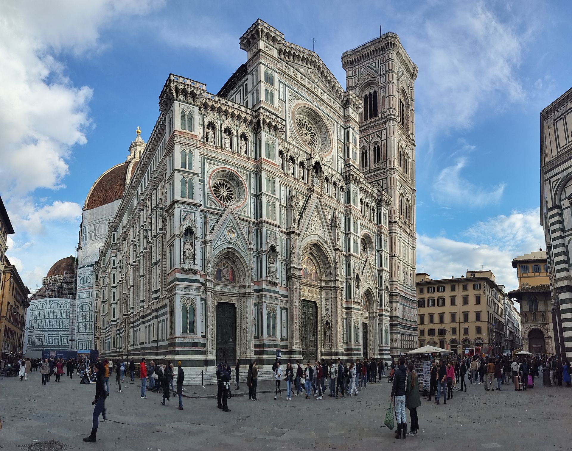 Duomo Cathedral in Florence, Italy, with detailed marble facade, dome, and bell tower; people gather in the square.