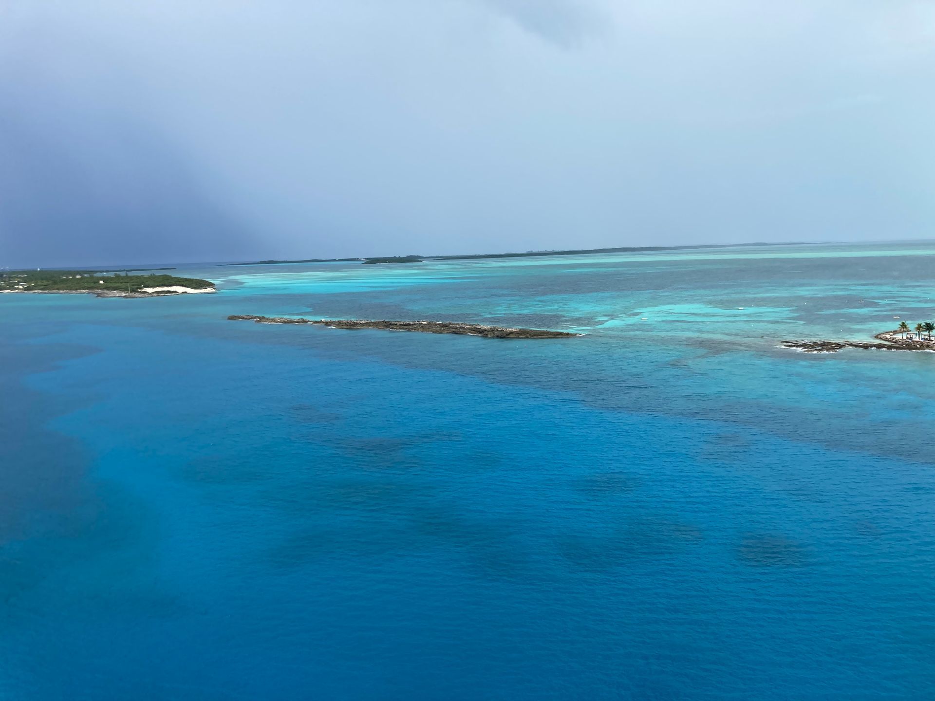 Person snowboarding down a snowy slope, arms outstretched. Other skiers and trees in the background.