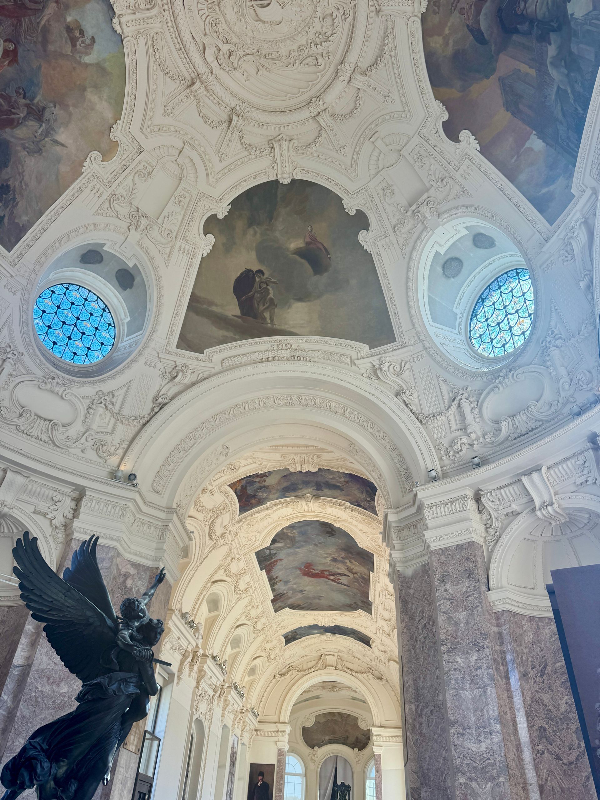 Looking up at the ceiling of the Petit Palais with a statue in the foreground in Paris, France.