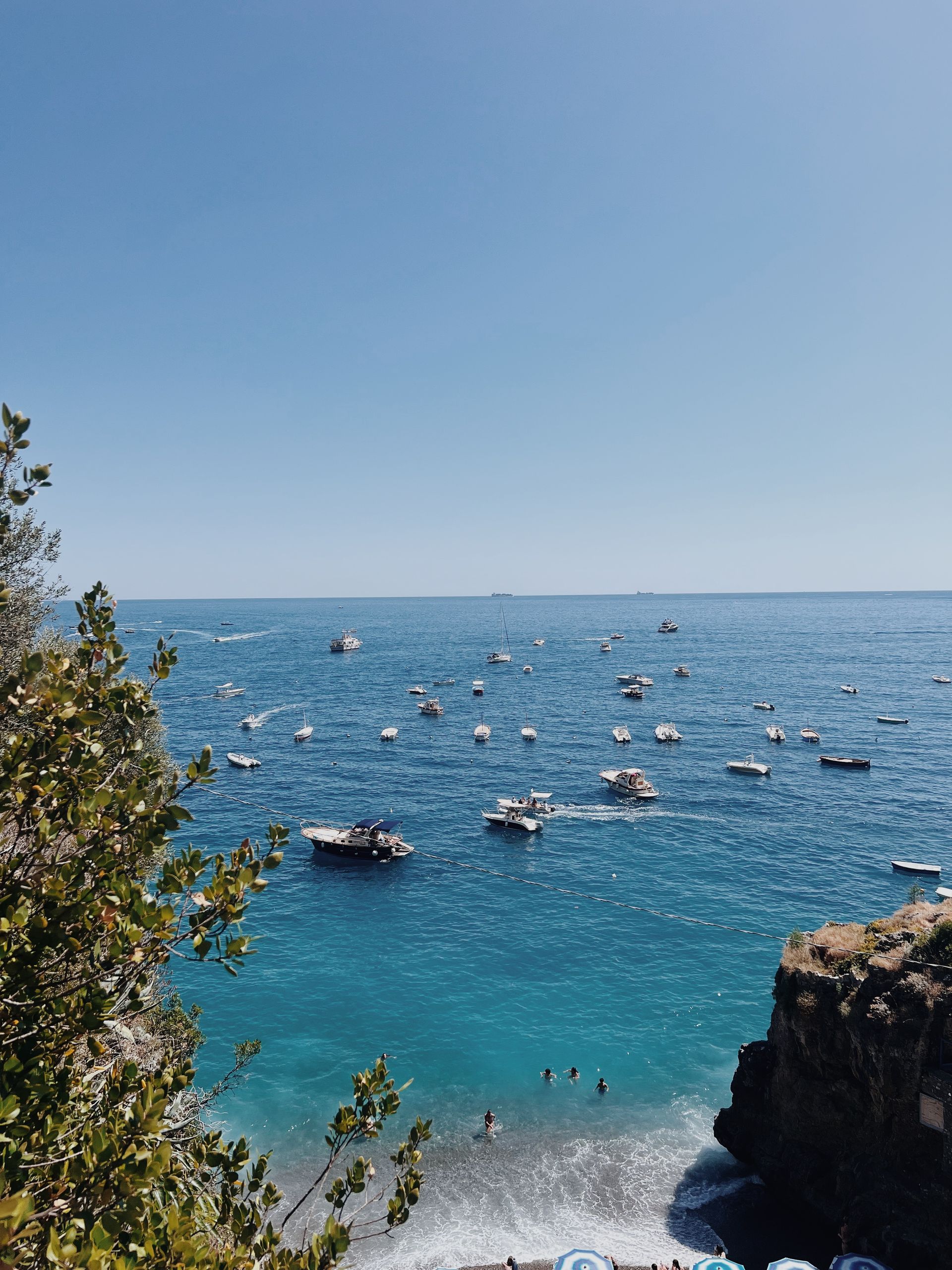 A cliff overlooking a body of water with boats in it in the Amalfi Coast, Italy.