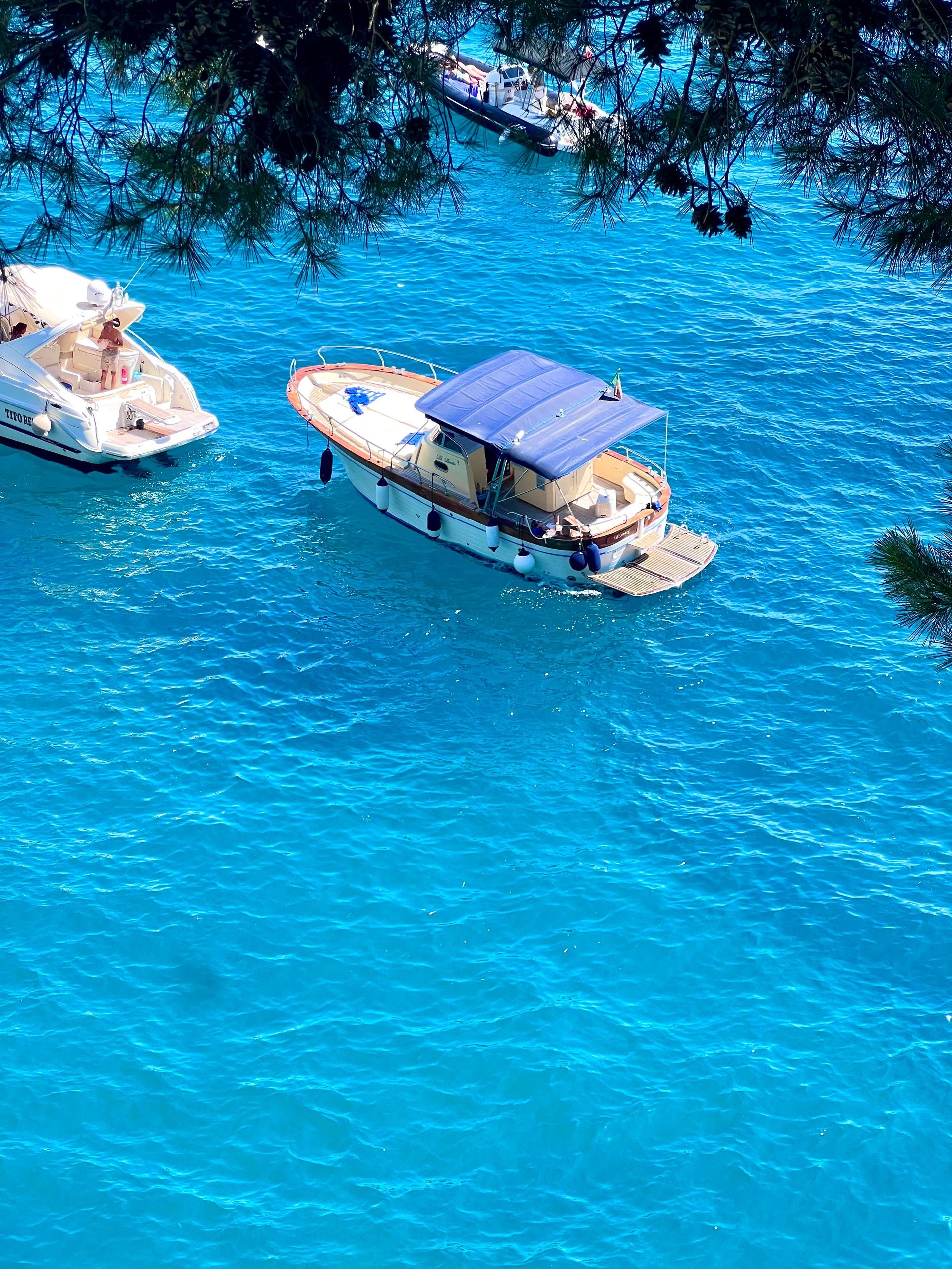 A boat with a blue roof is floating in the water in the Amalfi Coast, Italy.