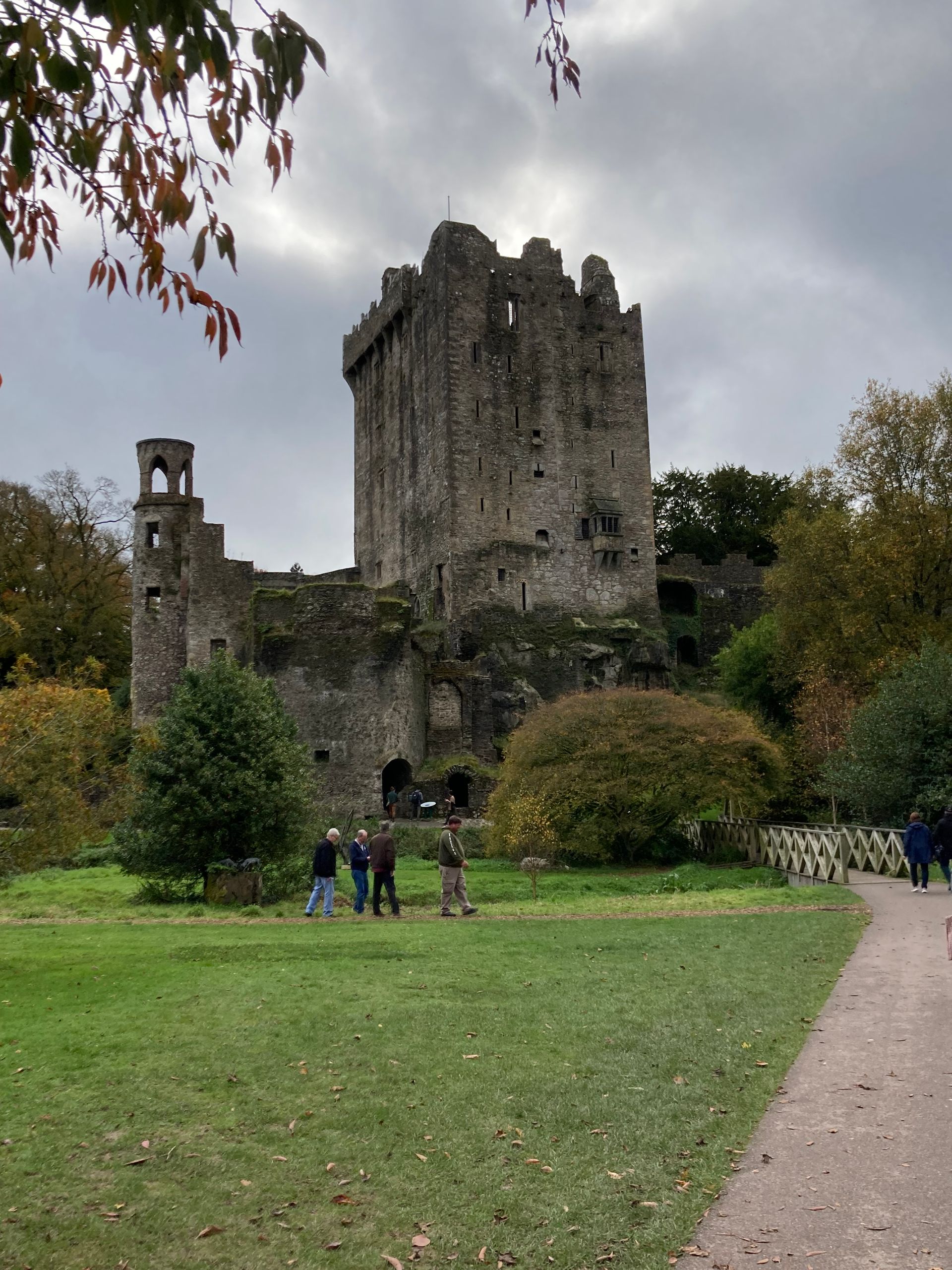 Stone castle ruin with green grass and path in Ireland. Overcast sky.