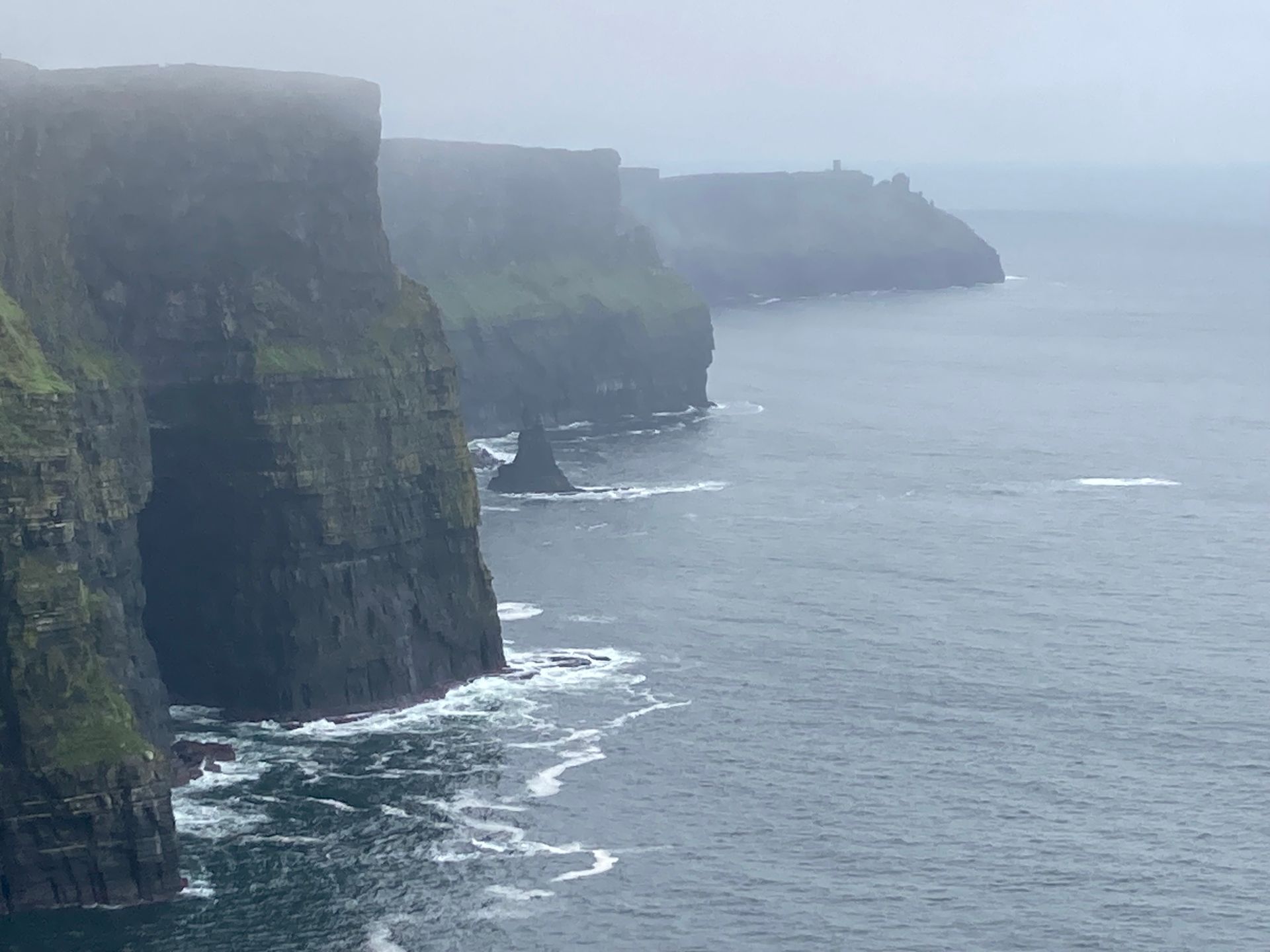 Cliffs of Moher in Ireland on a foggy day, with dark water and gray sky.