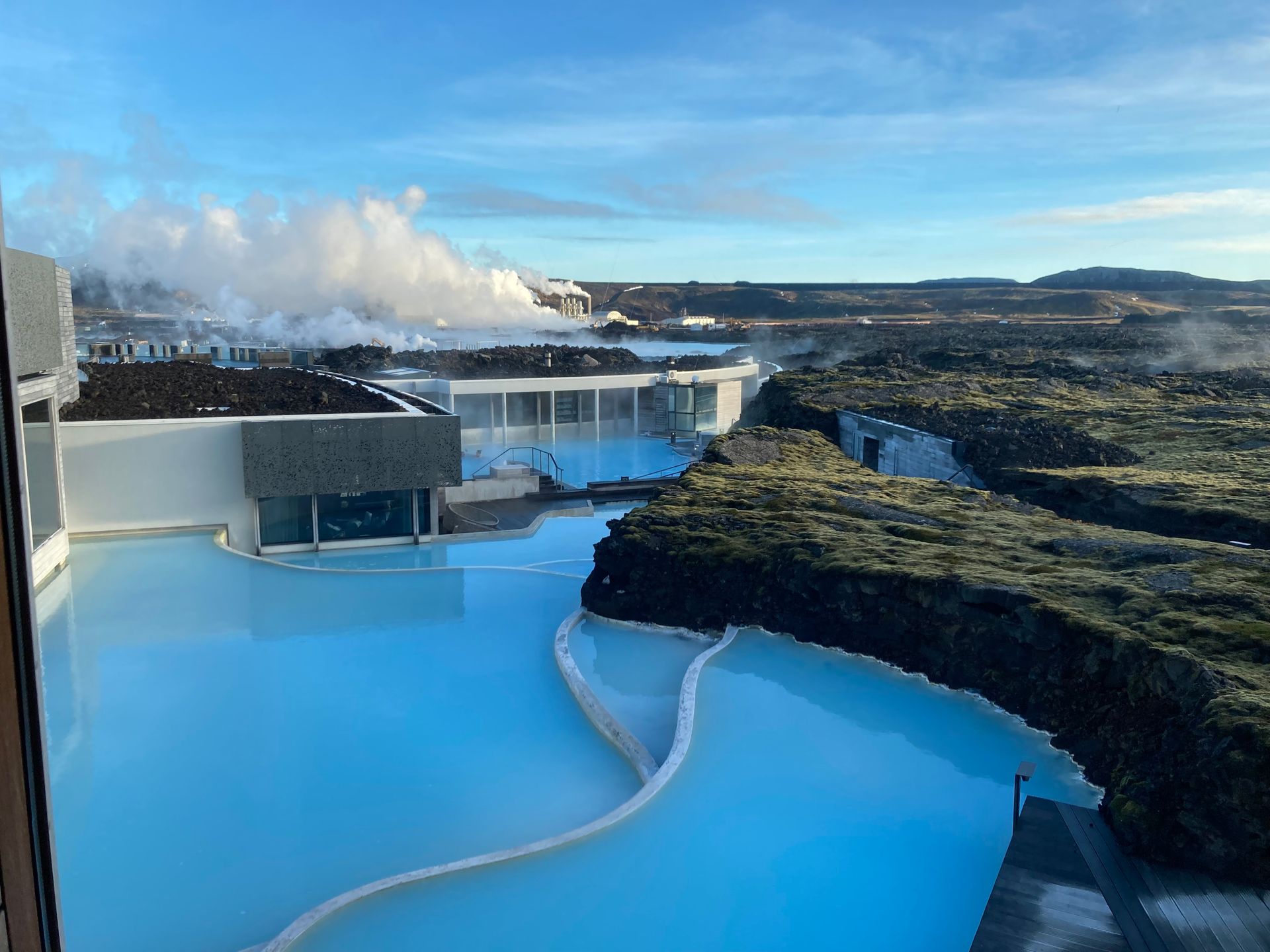 Blue Lagoon geothermal spa in Iceland; light blue water, black lava rock, and steam rising under a blue sky.