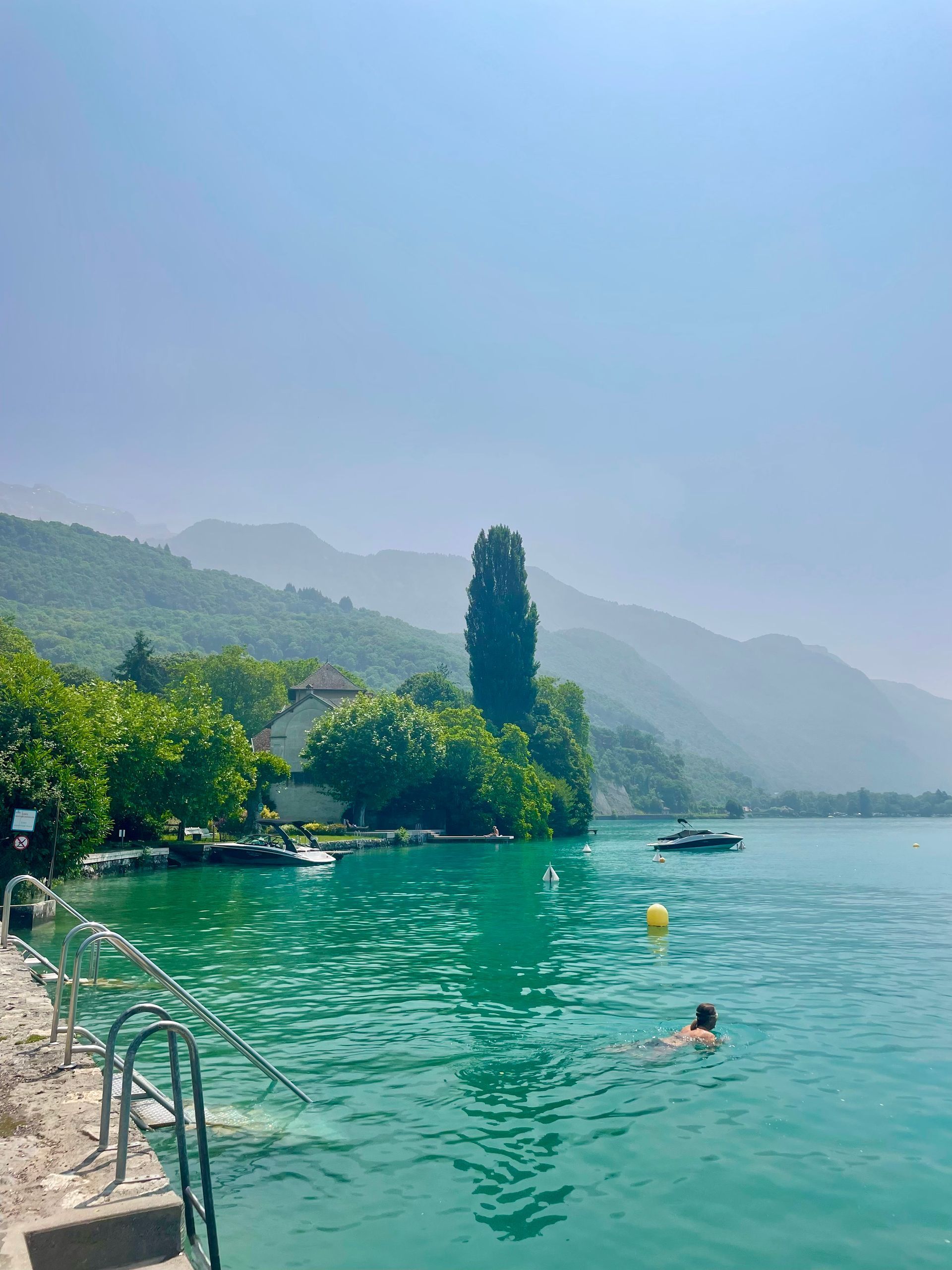 A person is swimming in Lake Annecy with mountains in the background in France.
