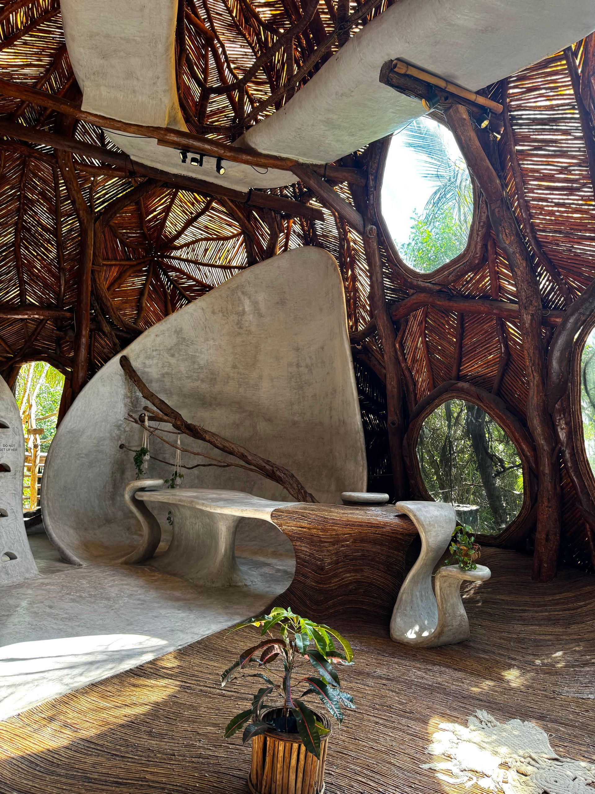 A room with a bench and a table in it at Azulik Sfer Ik museum in Tulum, Mexico.