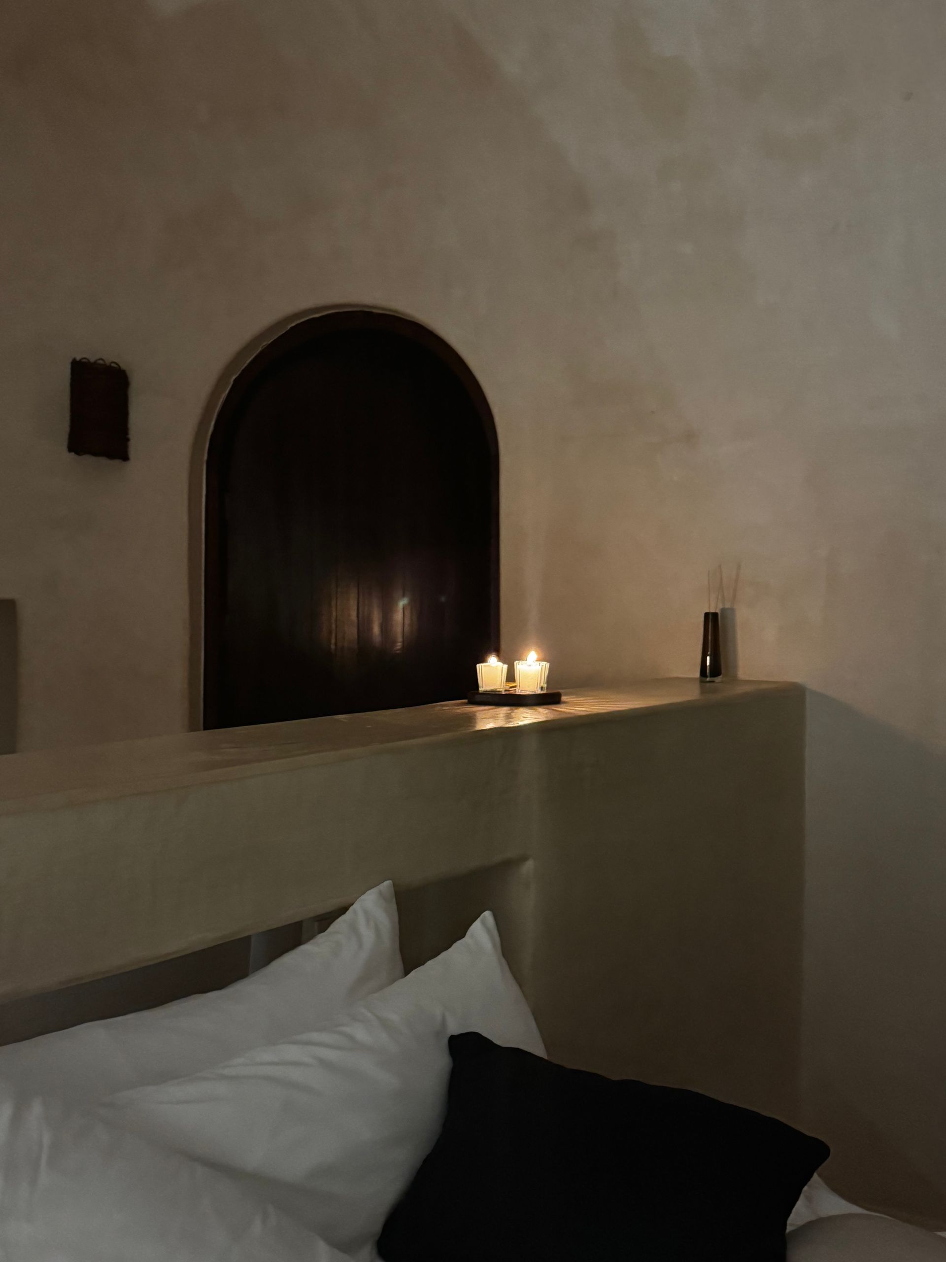 A bedroom with a bed , pillows , candles and a window at Papaya Playa Project hotel in Tulum, Mexico.