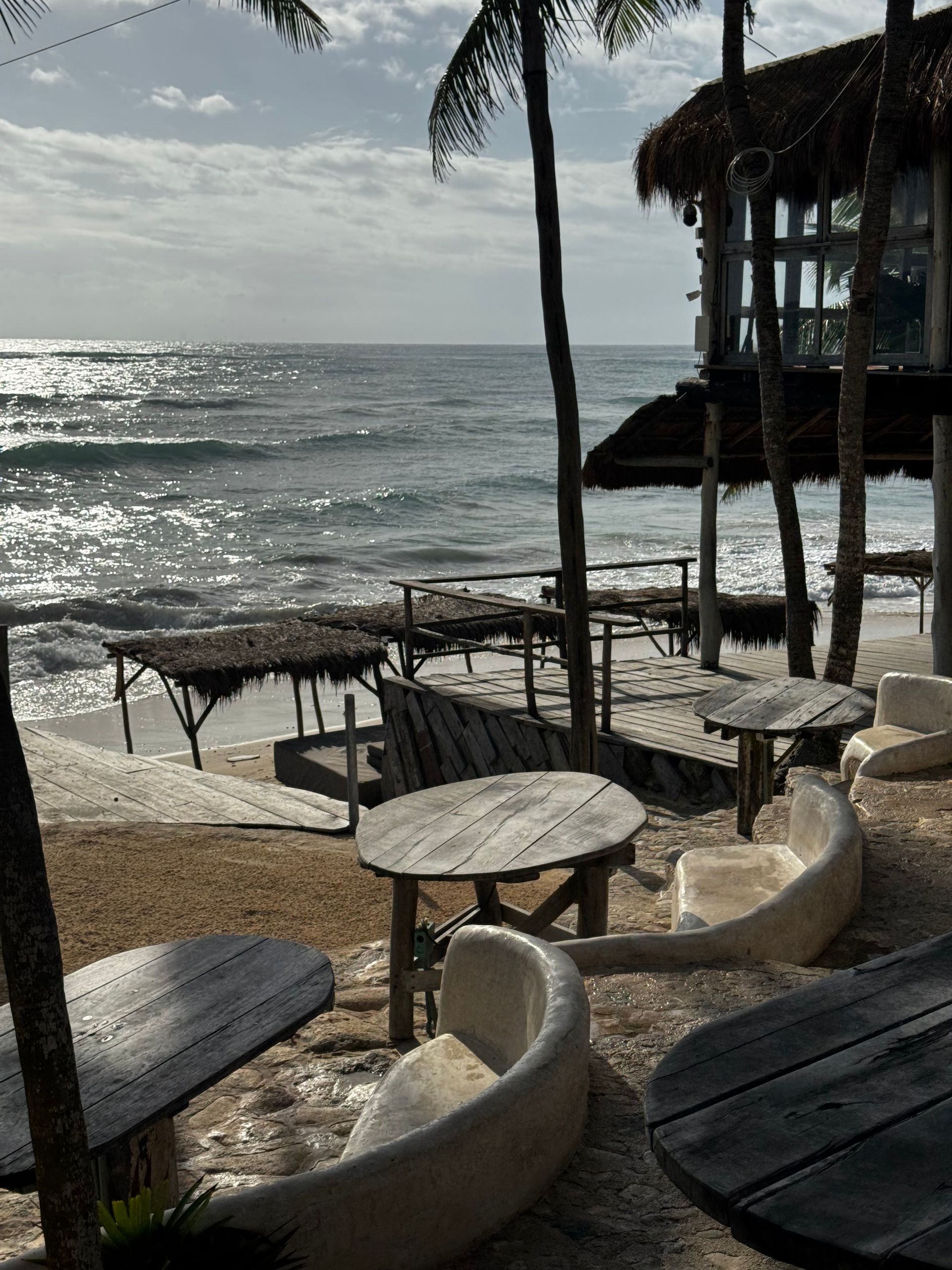 A beach with tables and chairs and a view of the ocean at Papaya Playa Project hotel in Tulum, Mexico.