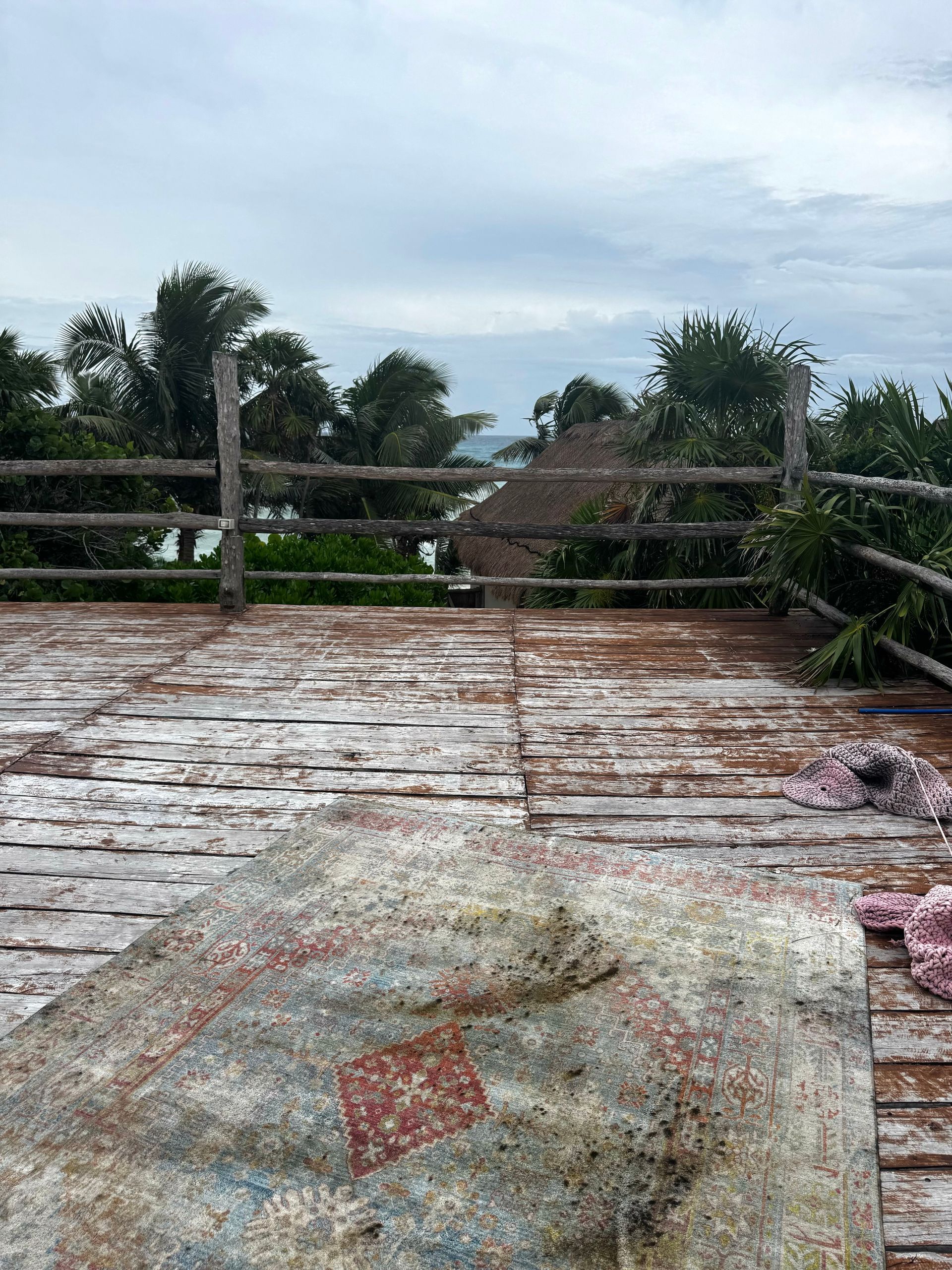 A wooden deck with a fence and trees in the background at Papaya Playa Project hotel in Tulum, Mexico.