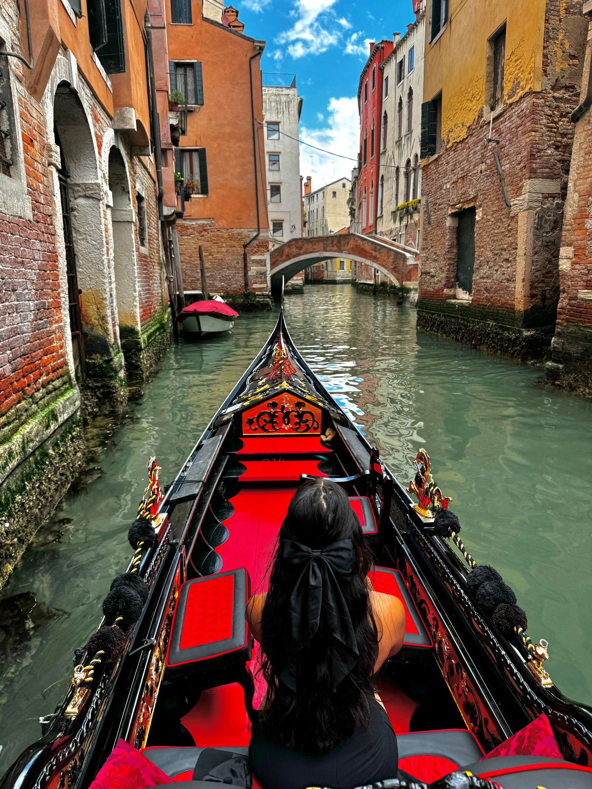 A woman is riding a gondola down a canal in venice.