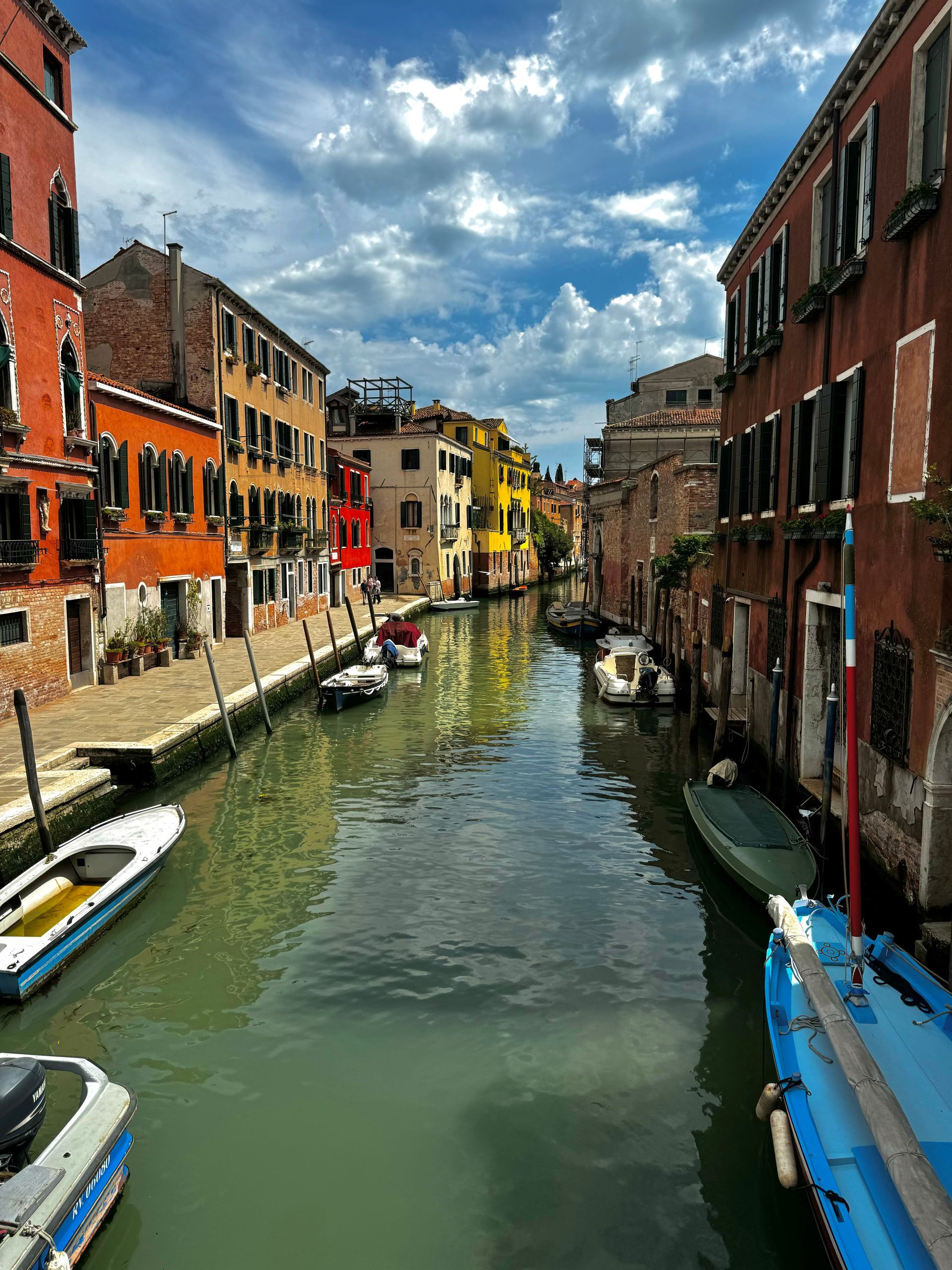 Canal in Venice, Italy, with colorful buildings, boats, and a cloudy sky.