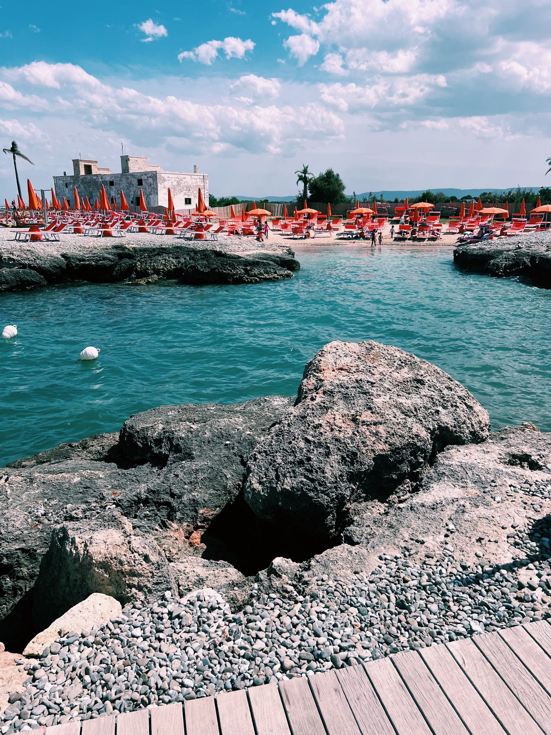 A beach with a lot of umbrellas and rocks in the foreground