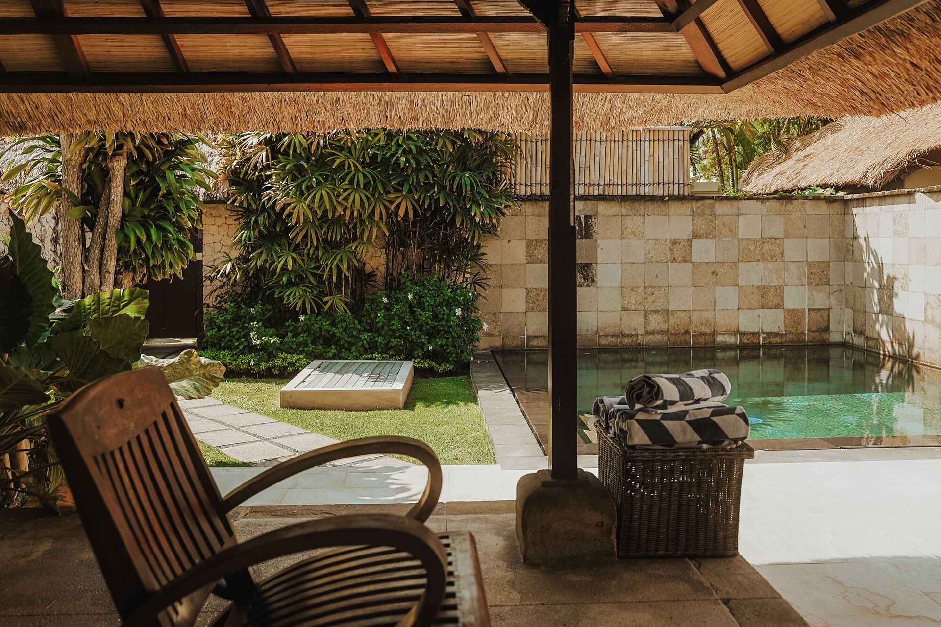 A wooden chair is sitting on a patio next to a swimming pool at a villa in Bali.