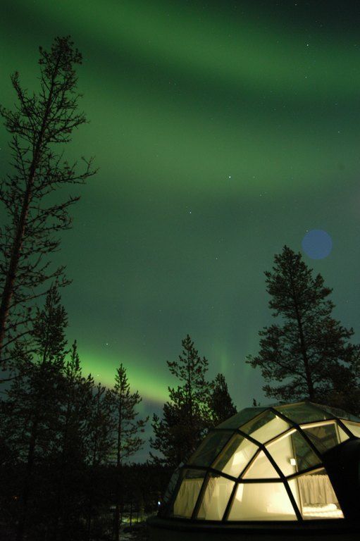 The aurora borealis is visible in the night sky above a glass dome in Finland.